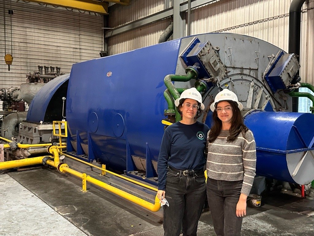 Anna and Katelyn in front of waste to energy equipment