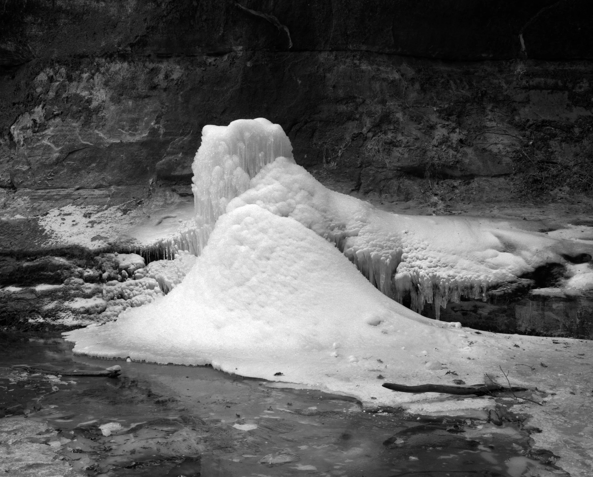 Ice formation on rocks near a water body with snow and ice.