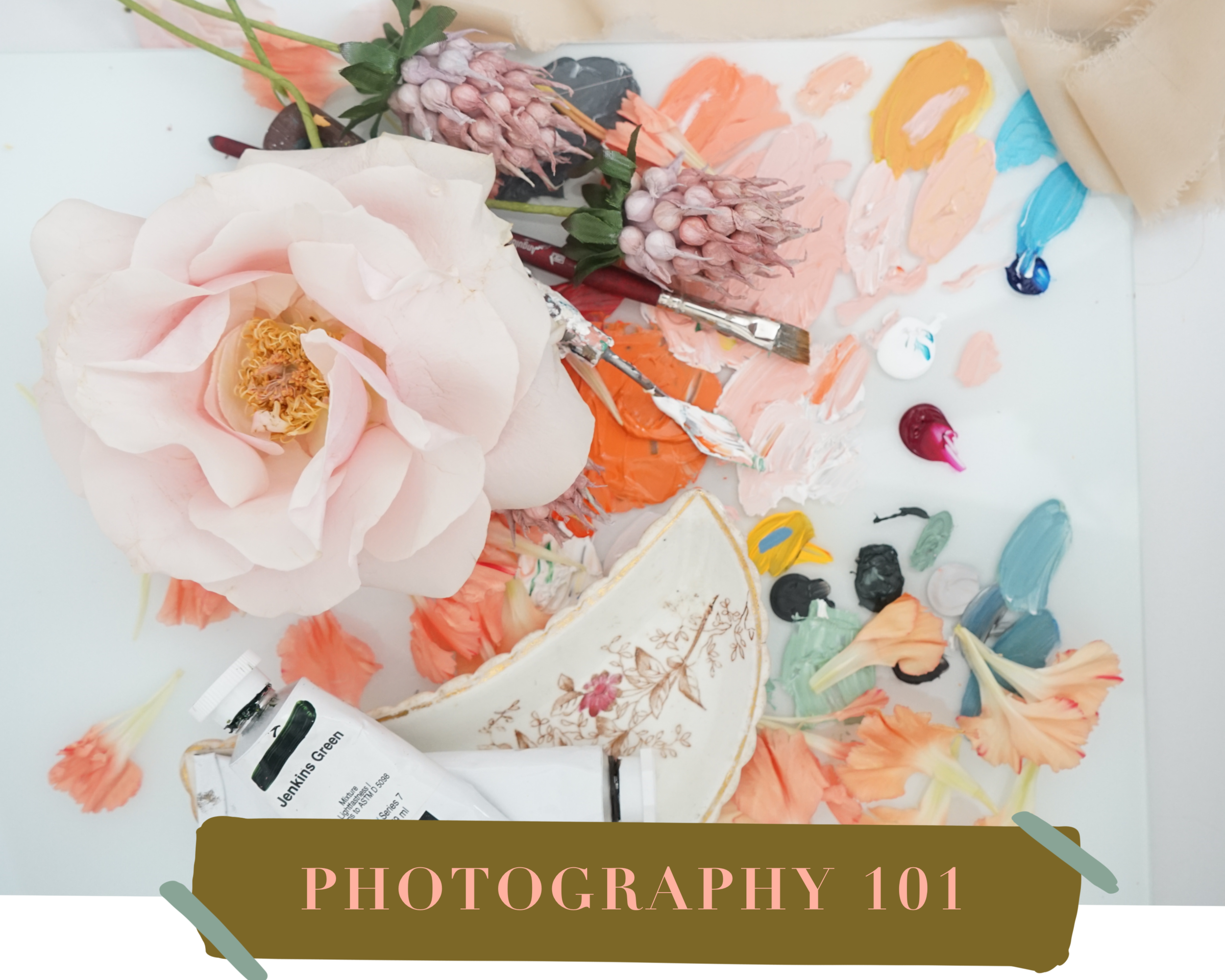 A floral arrangement on an artist's palette surrounded by paint tubes, brushes, and scattered flower petals, with a sign reading 'Photography 101' at the bottom.