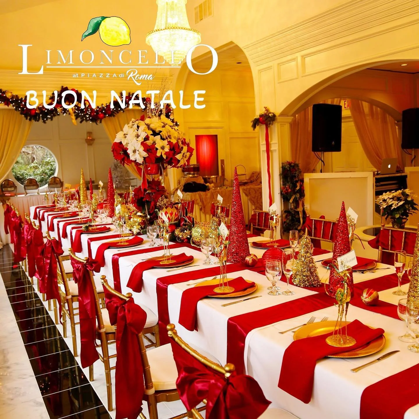 A long banquet table decorated for Christmas with red, gold, and white ornaments, poinsettias, and a centerpiece of white and red poinsettias, in a warmly lit room with holiday decor, garlands, and a chandelier.