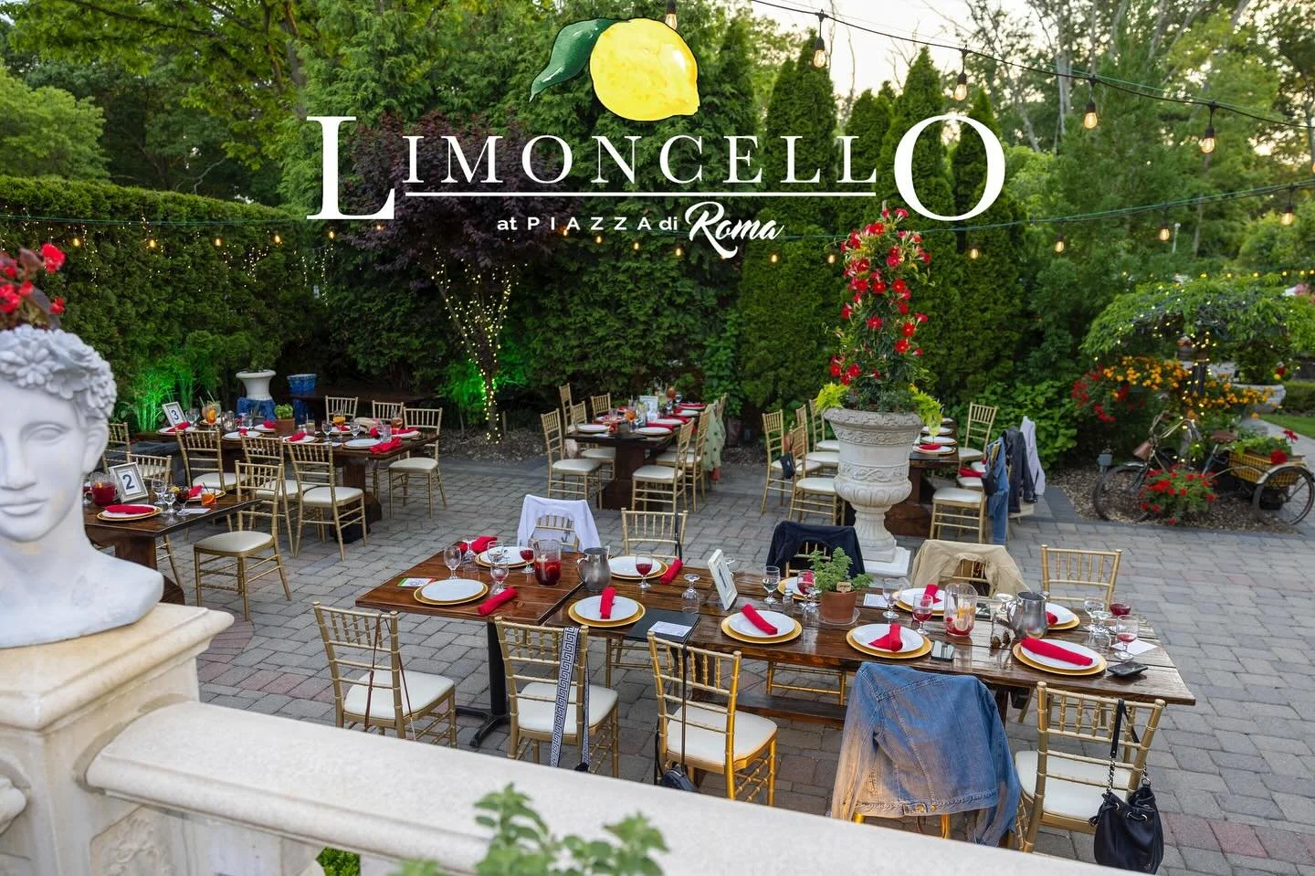 Outdoor dining setup at L'Imoncello, an Italian restaurant in Rome, with tables set with plates, glasses, napkins, surrounded by lush green trees and string lights.