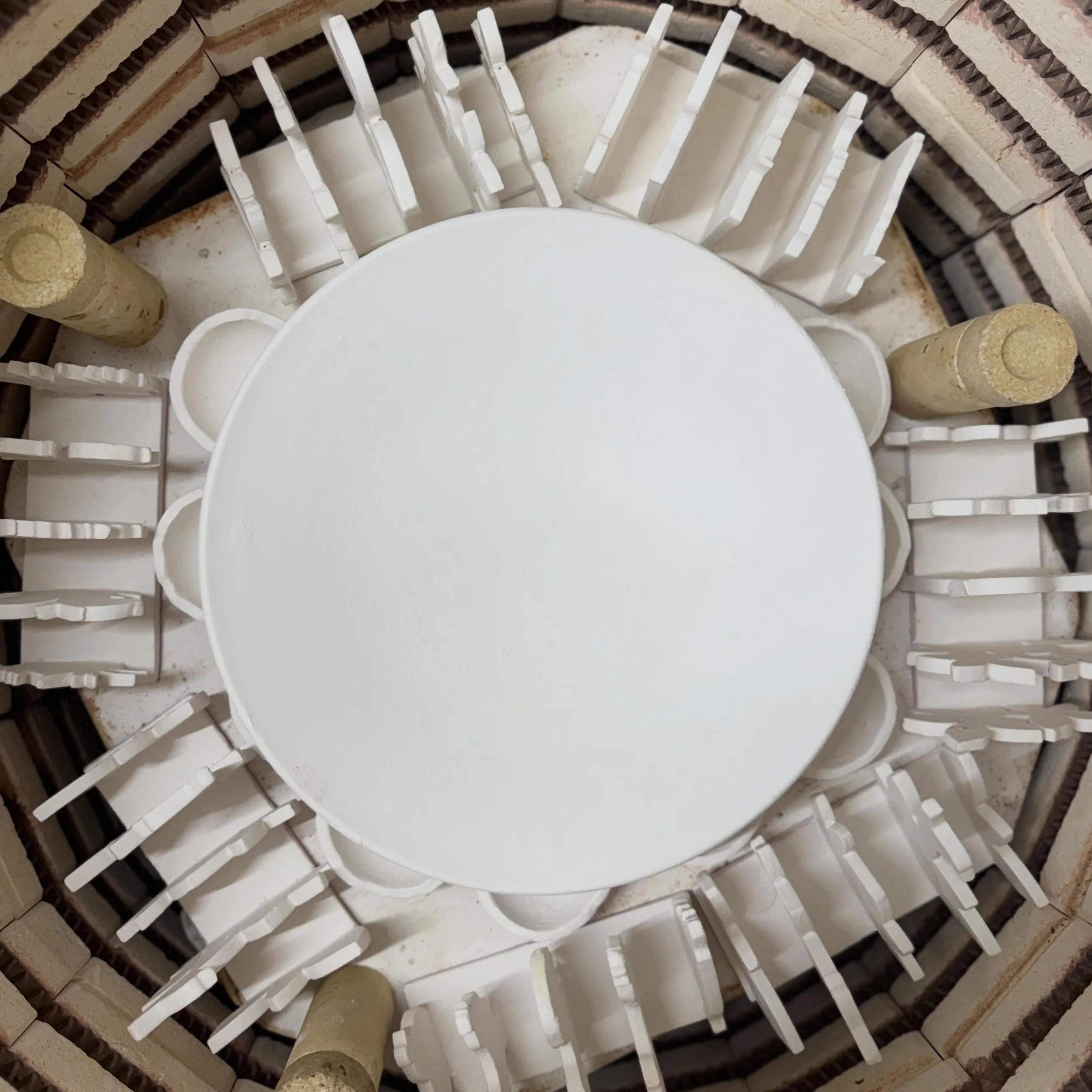 A glaze firing about to go on&hellip; I enjoy making patterns with the powdery white pots as I try to squeeze everything I can into each shelf. This is a ring of toast racks with a ring of tiny pots inside them and then one large serving bowl in the 