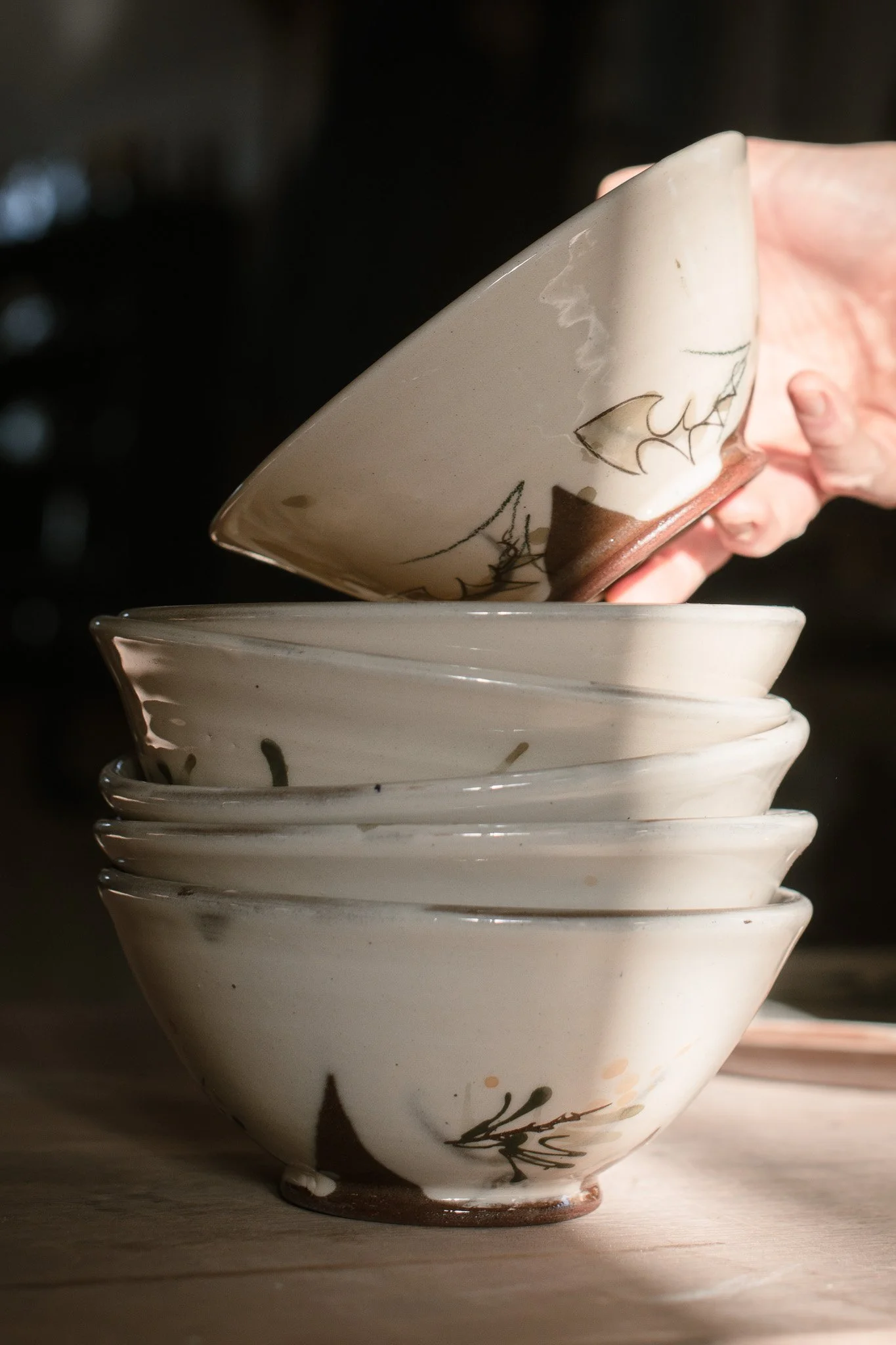 Hand reaching out to a stack of soup bowls