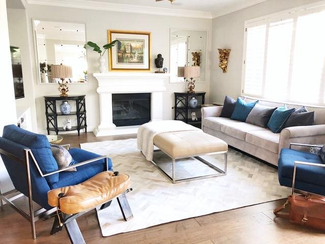 Residential interior design by Gin Treadwell Interiors, a living room with blue accent chairs, a leather ottoman, and layered neutral seating in Santa Clarita.