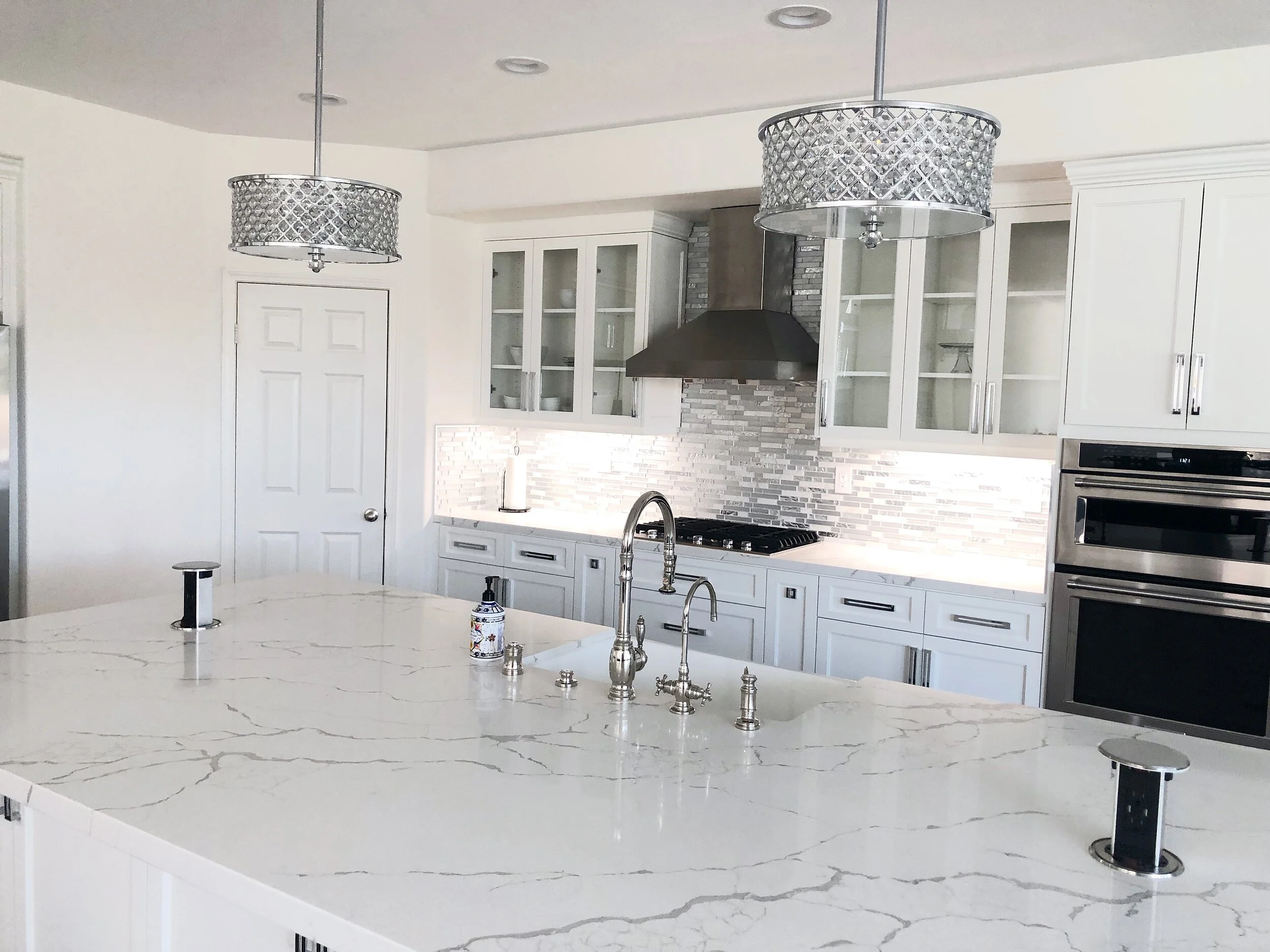 Modern farmhouse kitchen with a marble island and beaded drum pendant lights by Gin Treadwell Interiors in Los Angeles.