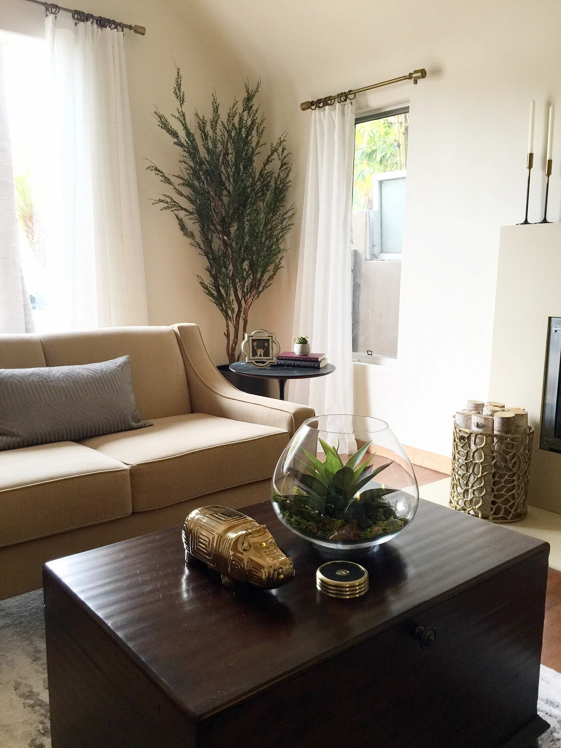 Spanish style living room with a plaster fireplace, gray accent chairs, an antique wood cabinet, and a warm orange throw by Gin Treadwell Interiors in Santa Clarita.