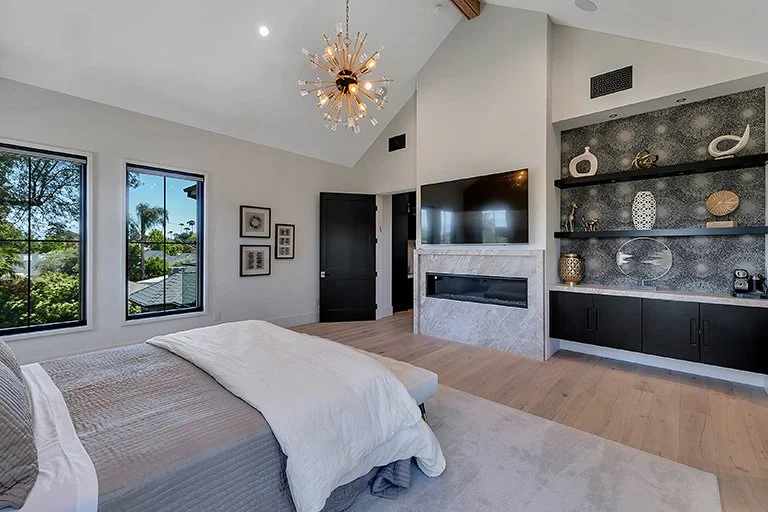 Organic modern bedroom with a built-in media wall and vaulted ceiling by Gin Treadwell Interiors in Santa Clarita.