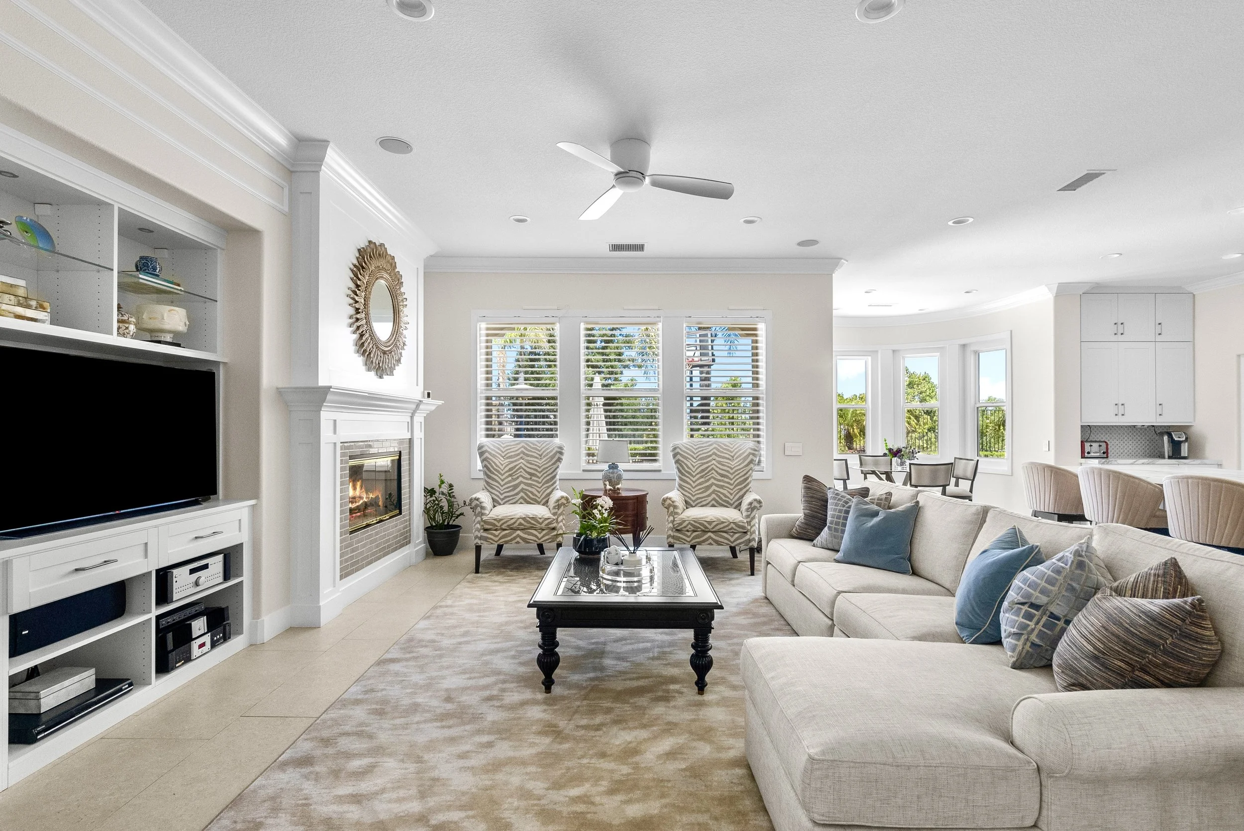 Traditional living room with a neutral sectional, classic coffee table, and large shuttered windows by Gin Treadwell Interiors in Santa Clarita.