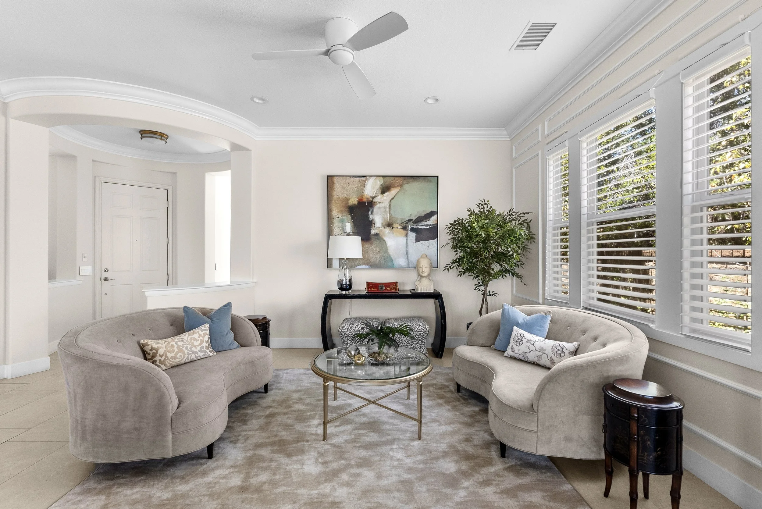 Traditional living room with neutral swivel chairs, layered seating, and framed artwork by Gin Treadwell Interiors in Santa Clarita.
