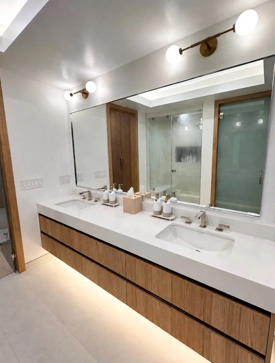 Organic modern primary bathroom with a floating double vanity and large mirrors by Gin Treadwell Interiors in Santa Clarita.