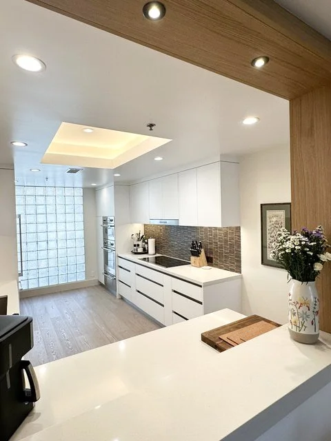 Japandi kitchen with white cabinets, backsplash, built-in oven, and a countertop with flowers by Gin Treadwell Interiors in Los Angeles.