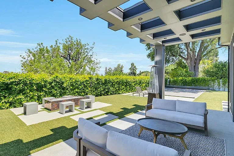 Organic modern backyard with a lawn, pergola, and outdoor seating by Gin Treadwell Interiors in Santa Clarita.