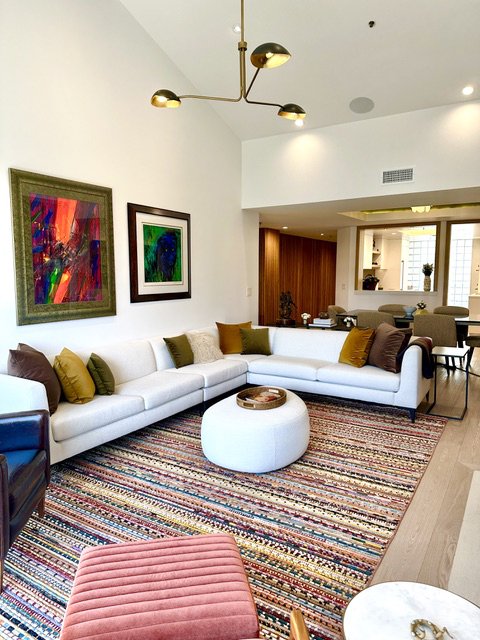 Organic modern living room with a colorful upholstered bench, sectional, and bold art by Gin Treadwell Interiors in Santa Clarita.