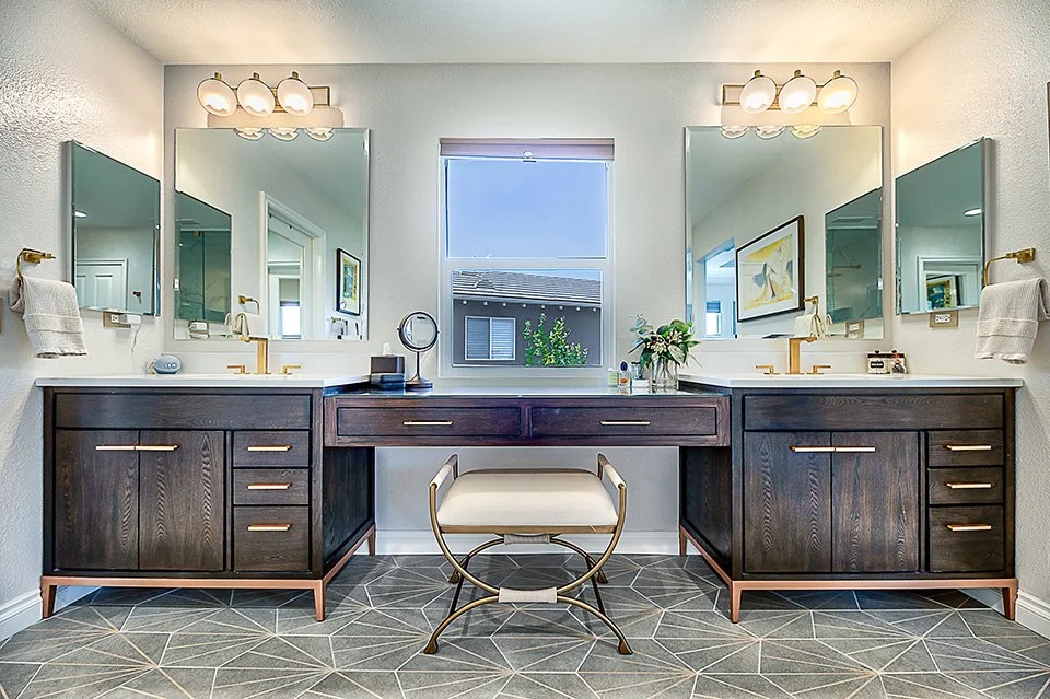 Transitional primary bathroom with a double vanity, dark wood cabinetry, and large mirrors by Gin Treadwell Interiors in Santa Clarita.