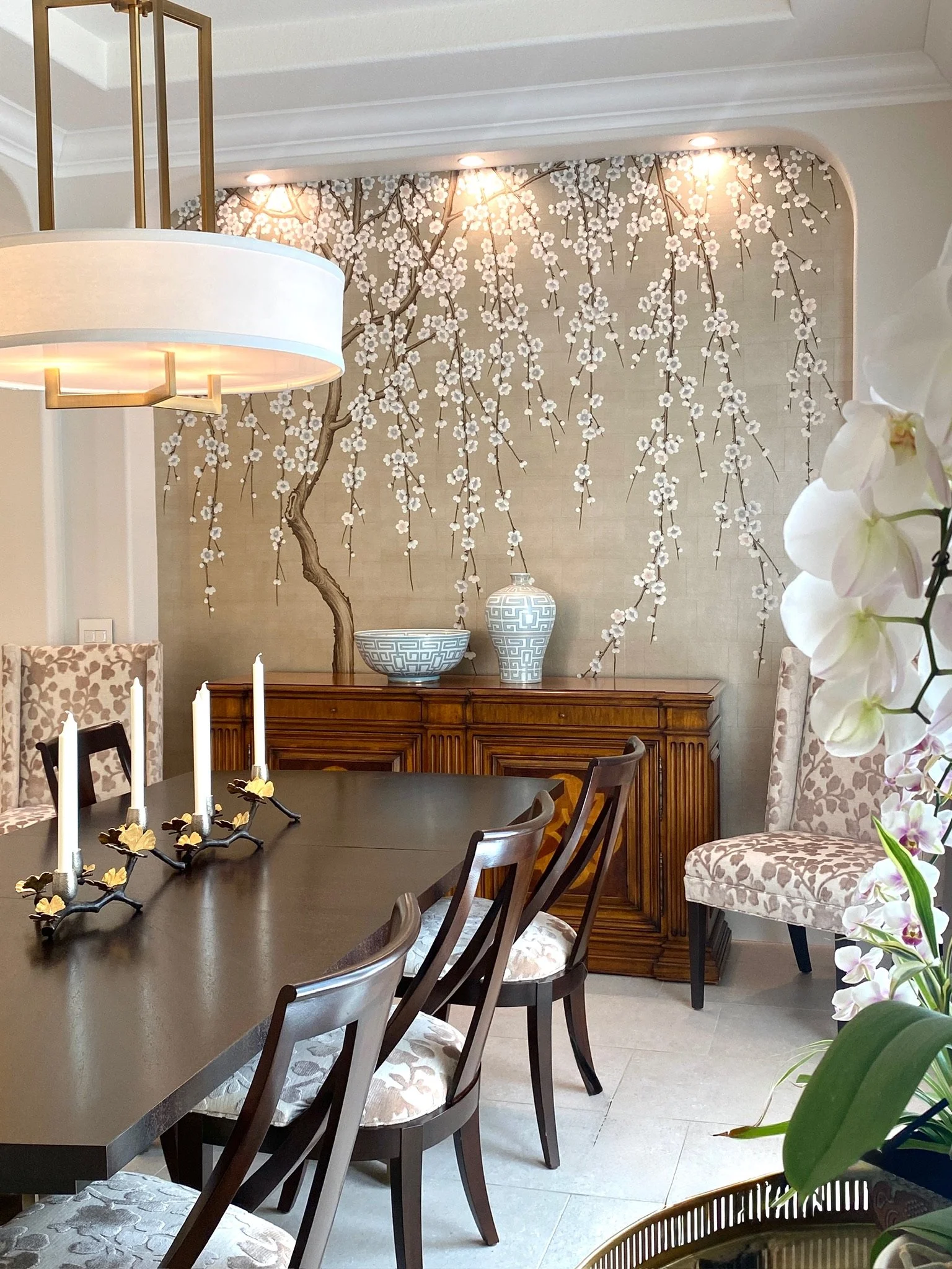 Residential interior design by Gin Treadwell Interiors, a dining room with a cherry blossom mural, a dark wood table, and patterned upholstered chairs in Santa Clarita.