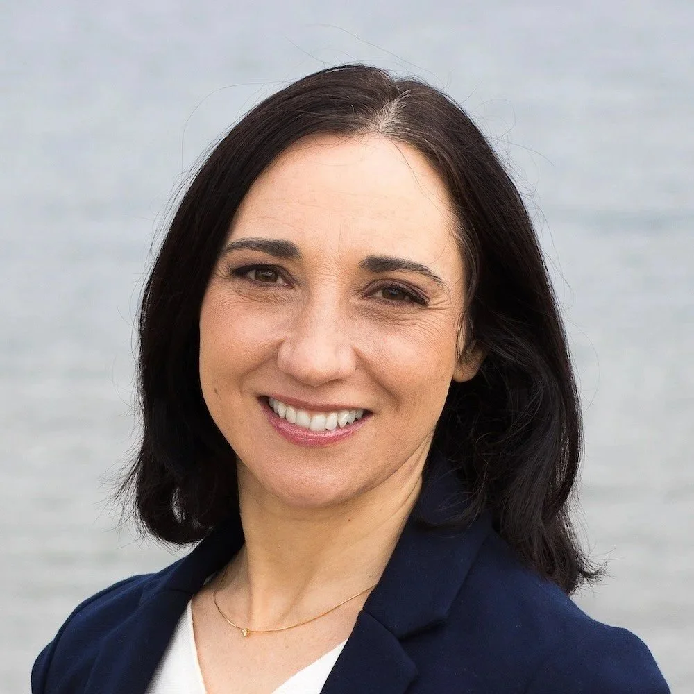 Alba REverte, English-speaking therapist and certified coach in Stockholm, smiling in a professional headshot with a blurred outdoor background.