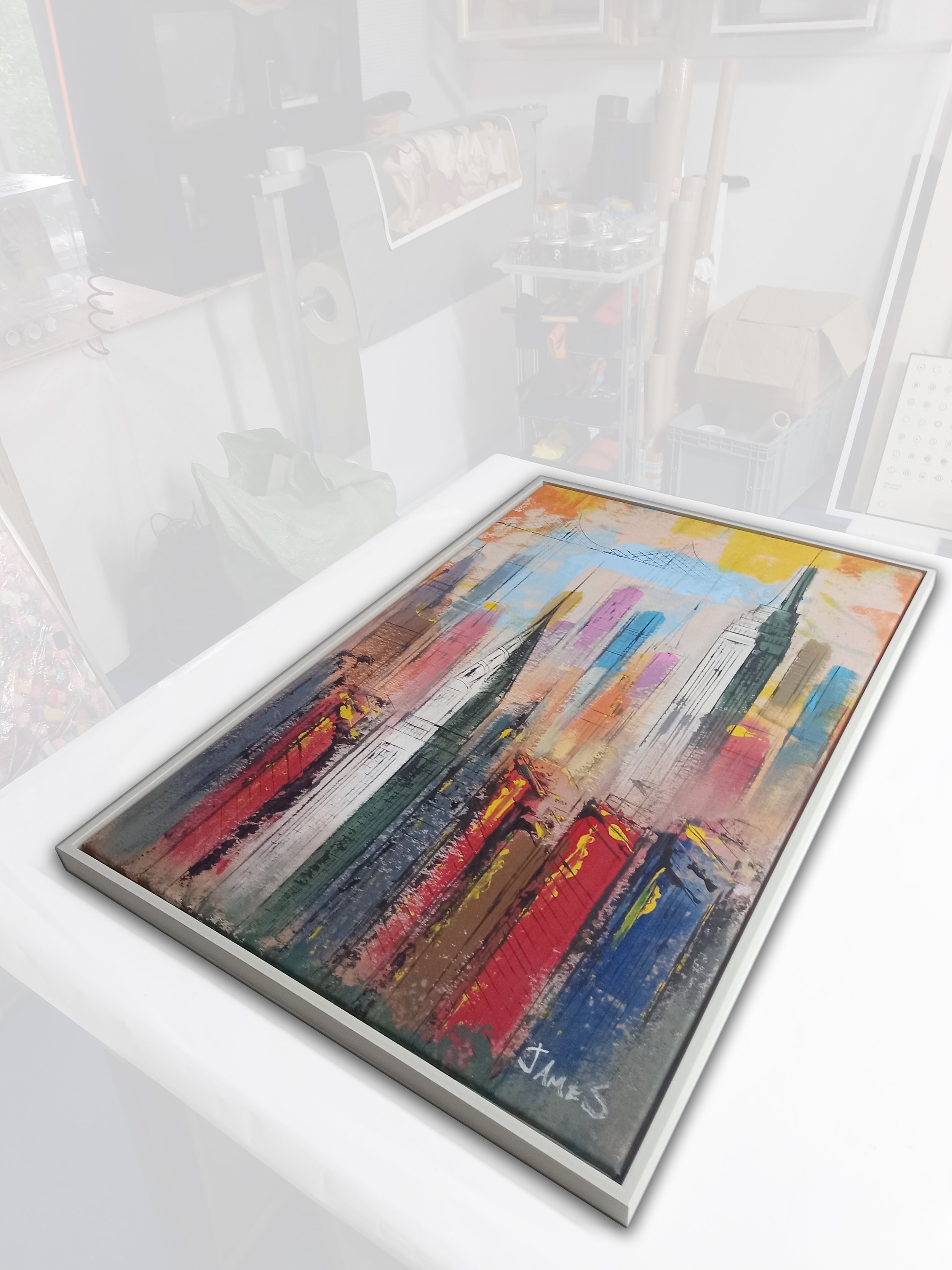 A framed colorful abstract painting with bold, sweeping brushstrokes in various shades of red, orange, yellow, blue, green, and black.