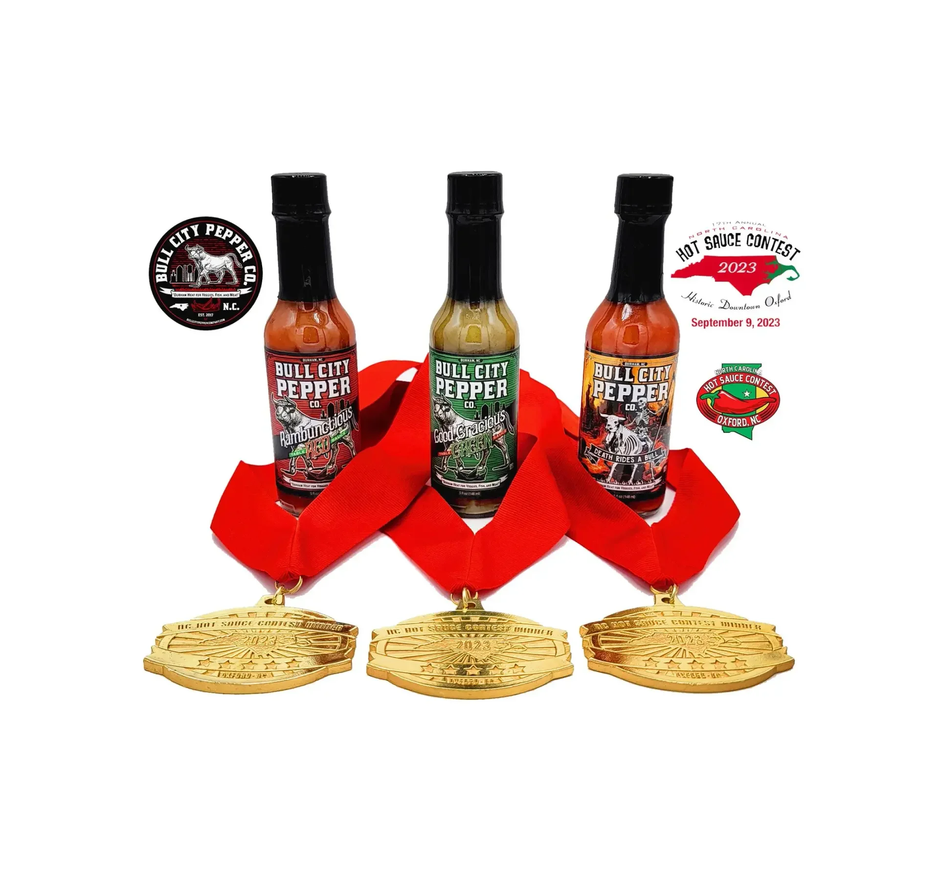 Three bottles of Bull City Pepper hot sauce with red medals in front, medals inscribed with 'North Carolina Hot Sauce Champions' and 2023, 2025, and additional badges indicating the contest took place in Oxford, North Carolina, on September 9, 2024.