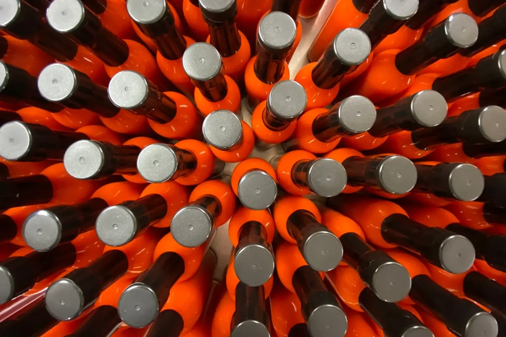 Top-down view of numerous orange and black bottled beverages arranged in a circular pattern.