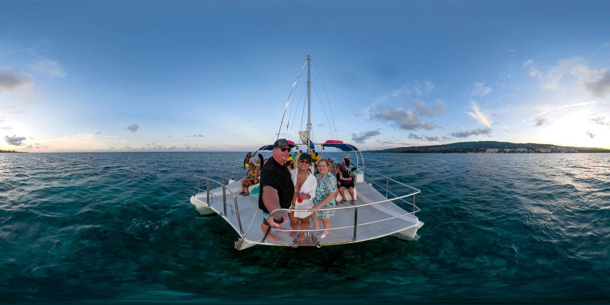Travelers gathered on the bow of a catamaran surrounded by the Caribbean Sea in Jamaica.