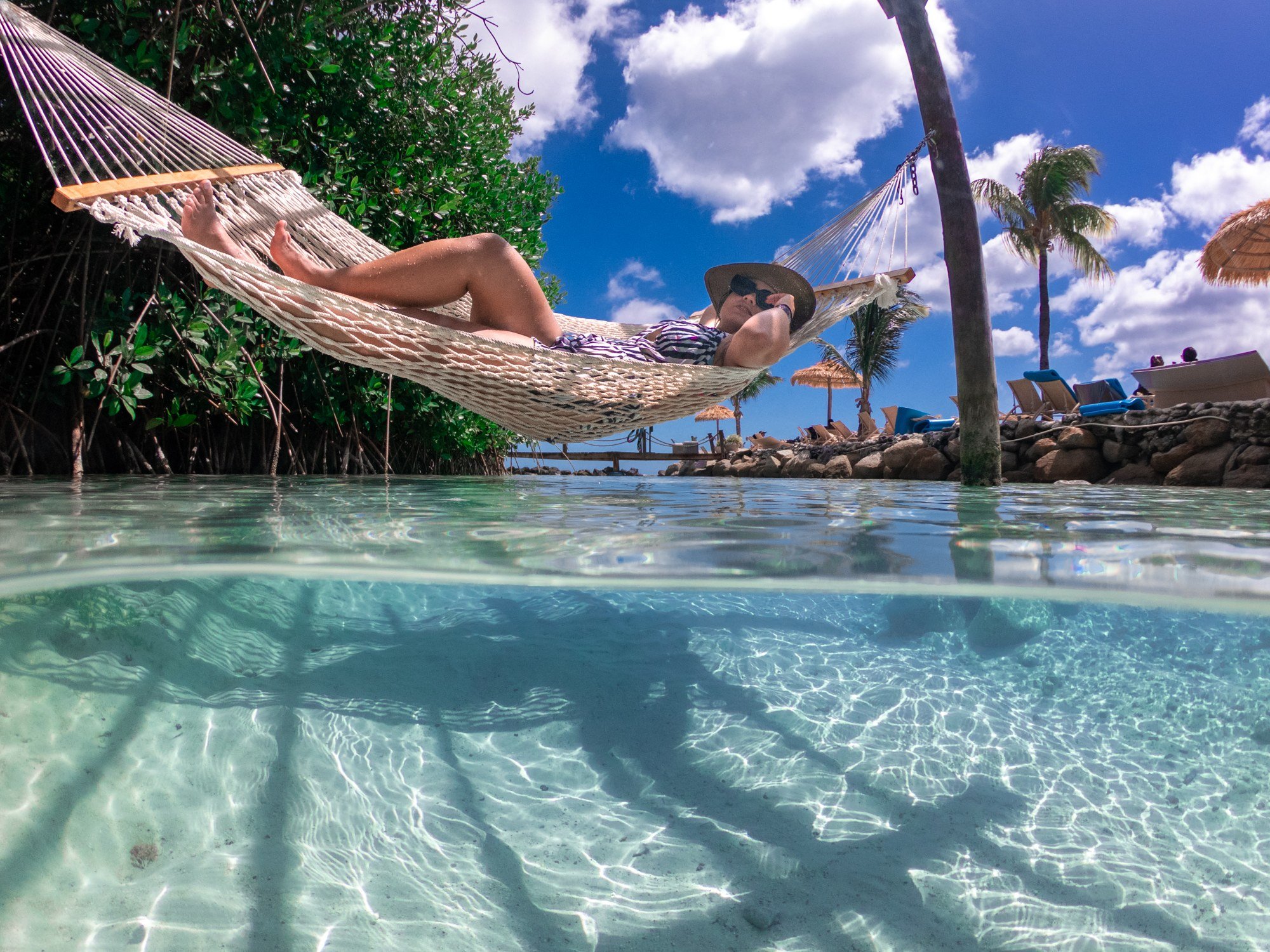 Woman relaxing in a hammock over turquoise water at Renaissance Island