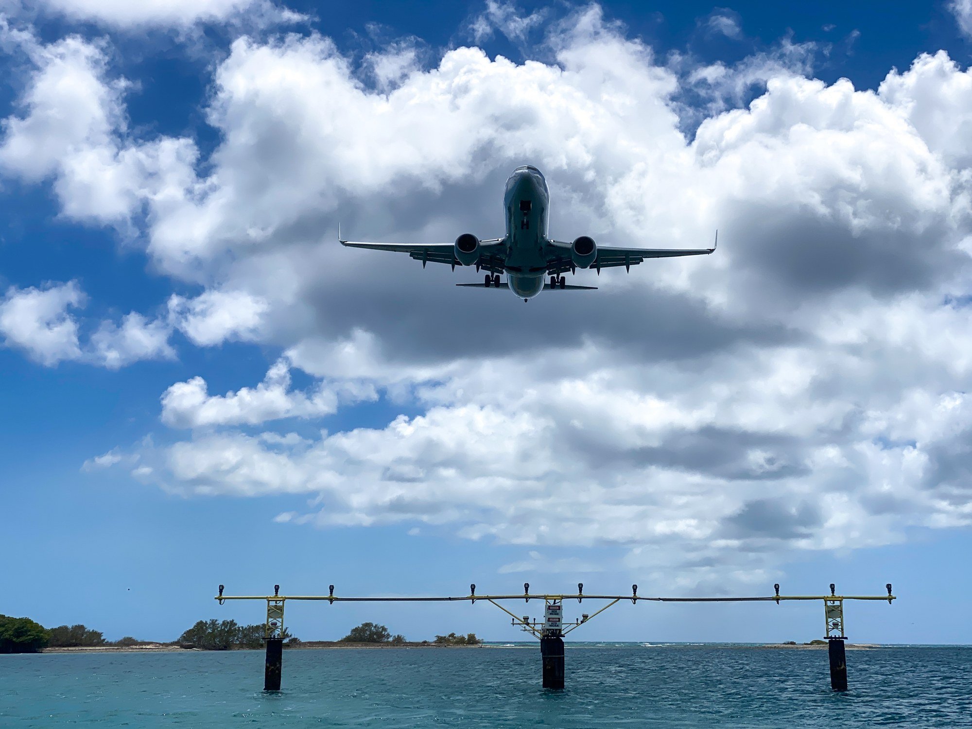 Airplane landing over turquoise water near Renaissance Island in Aruba