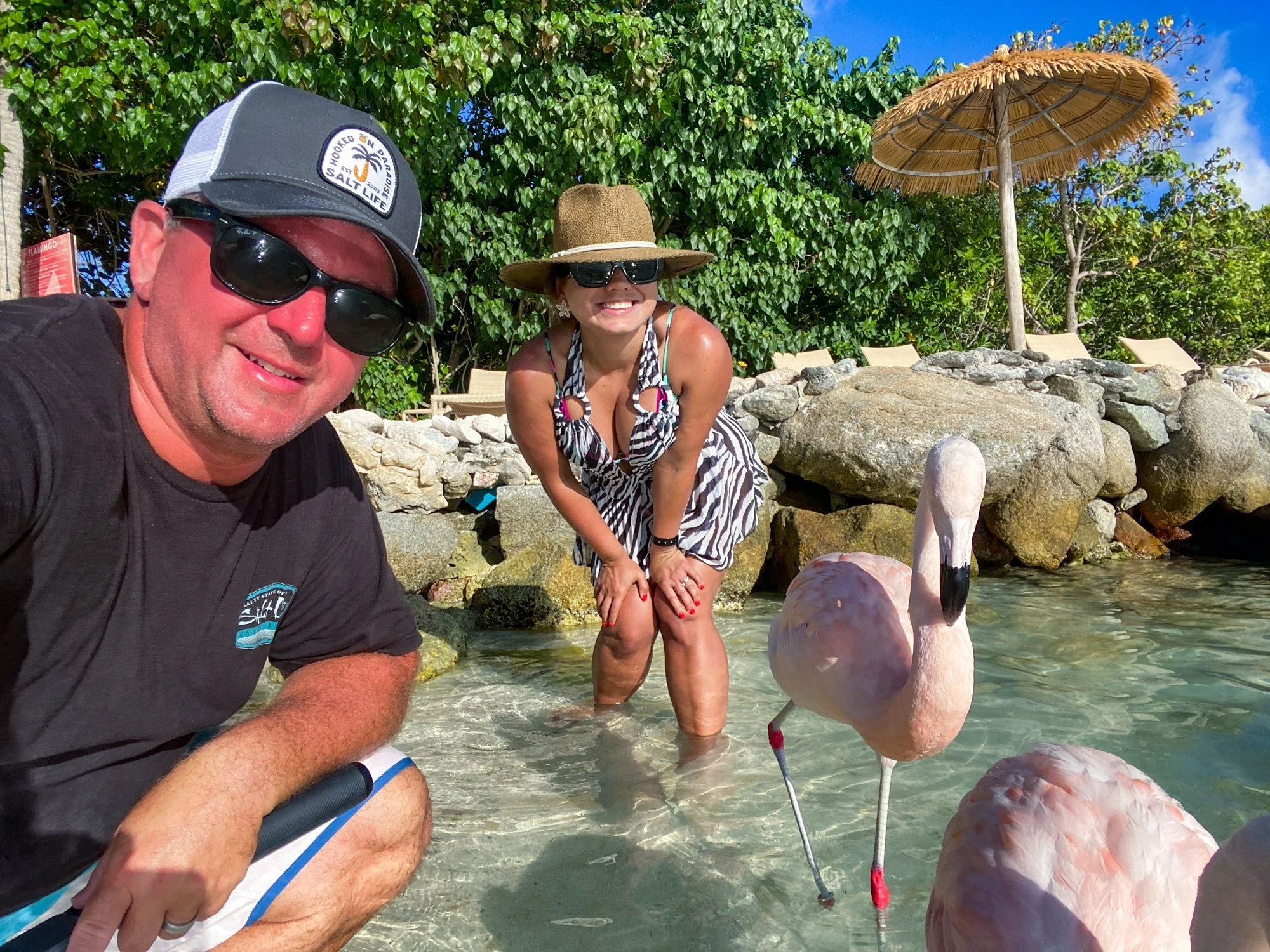 Couple posing with flamingos in shallow water at Renaissance Island