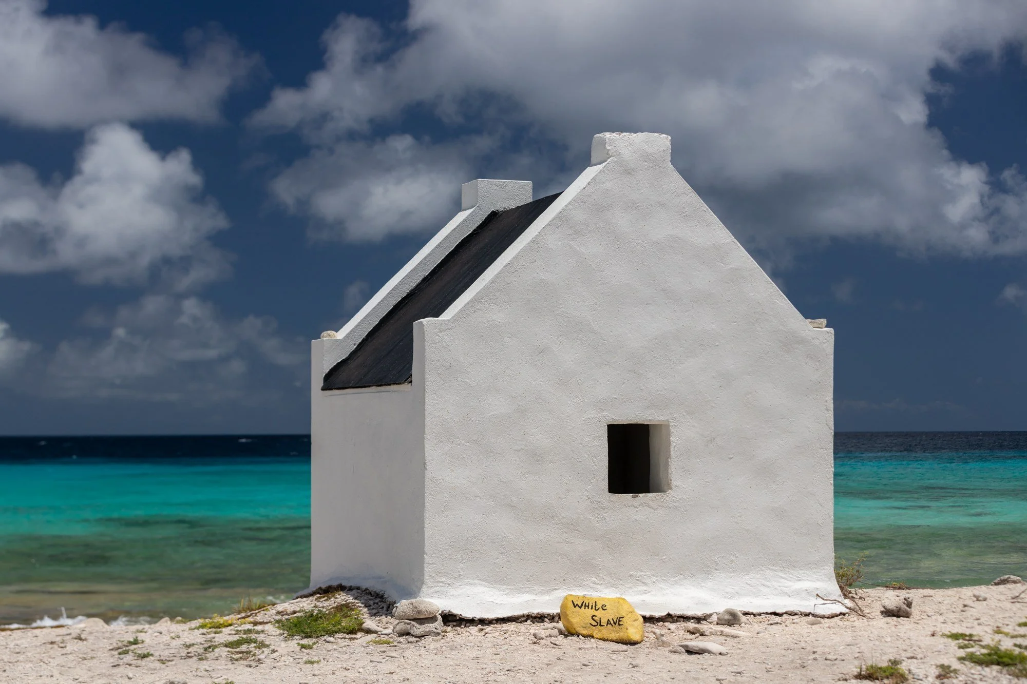 Historic white slave hut beside the turquoise sea in Bonaire