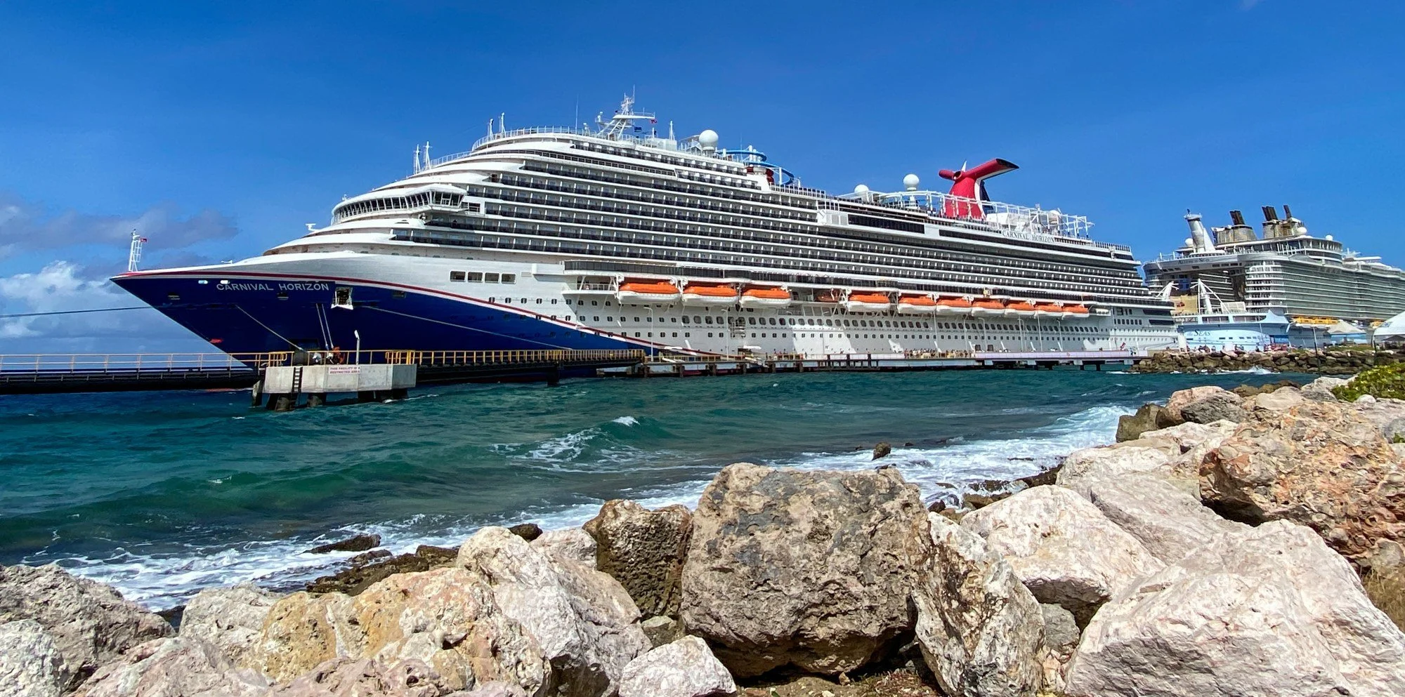 Carnival Horizon docked behind the rocky shoreline in Curaçao