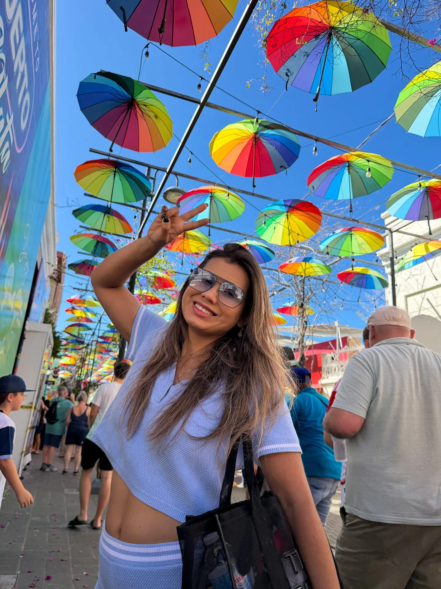 Traveler posing beneath colorful hanging umbrellas at Taino Bay in Puerto Plata.