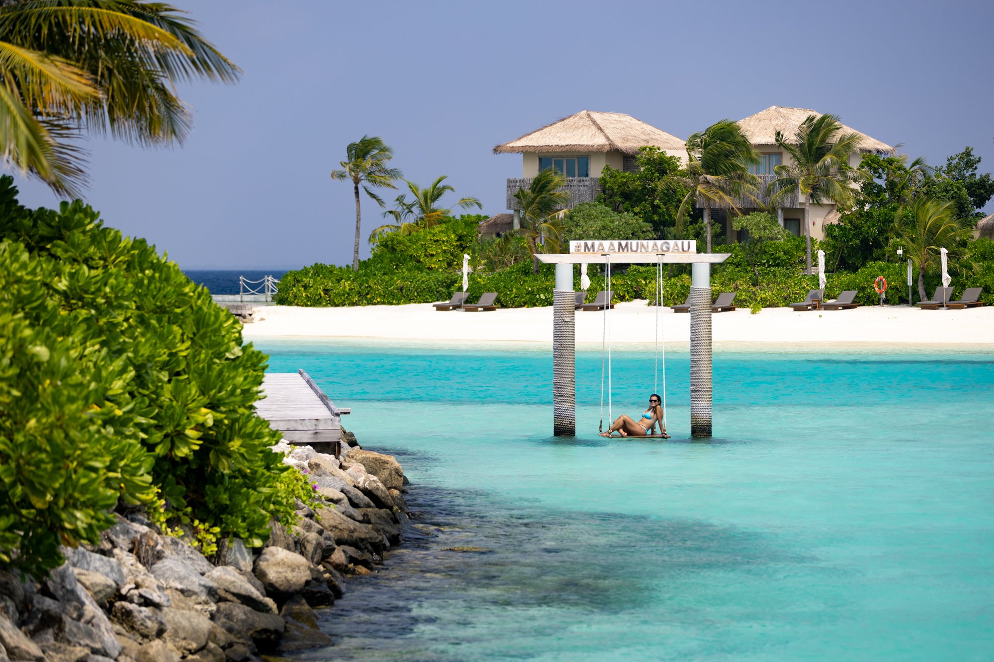 Overwater swing framed by a bright turquoise lagoon at a Maldives island resort.