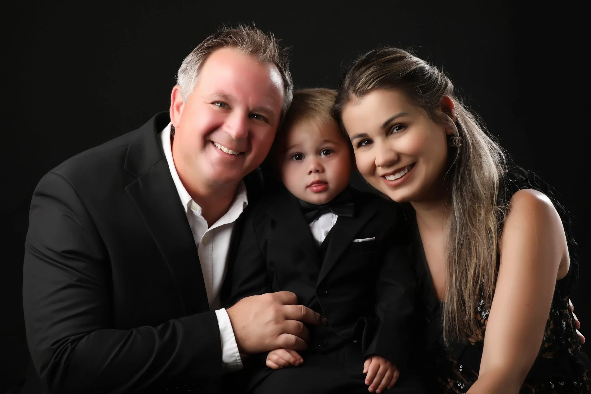 Formal black-background portrait of Jason, Amanda and Daniel during their Mother’s Day cruise.