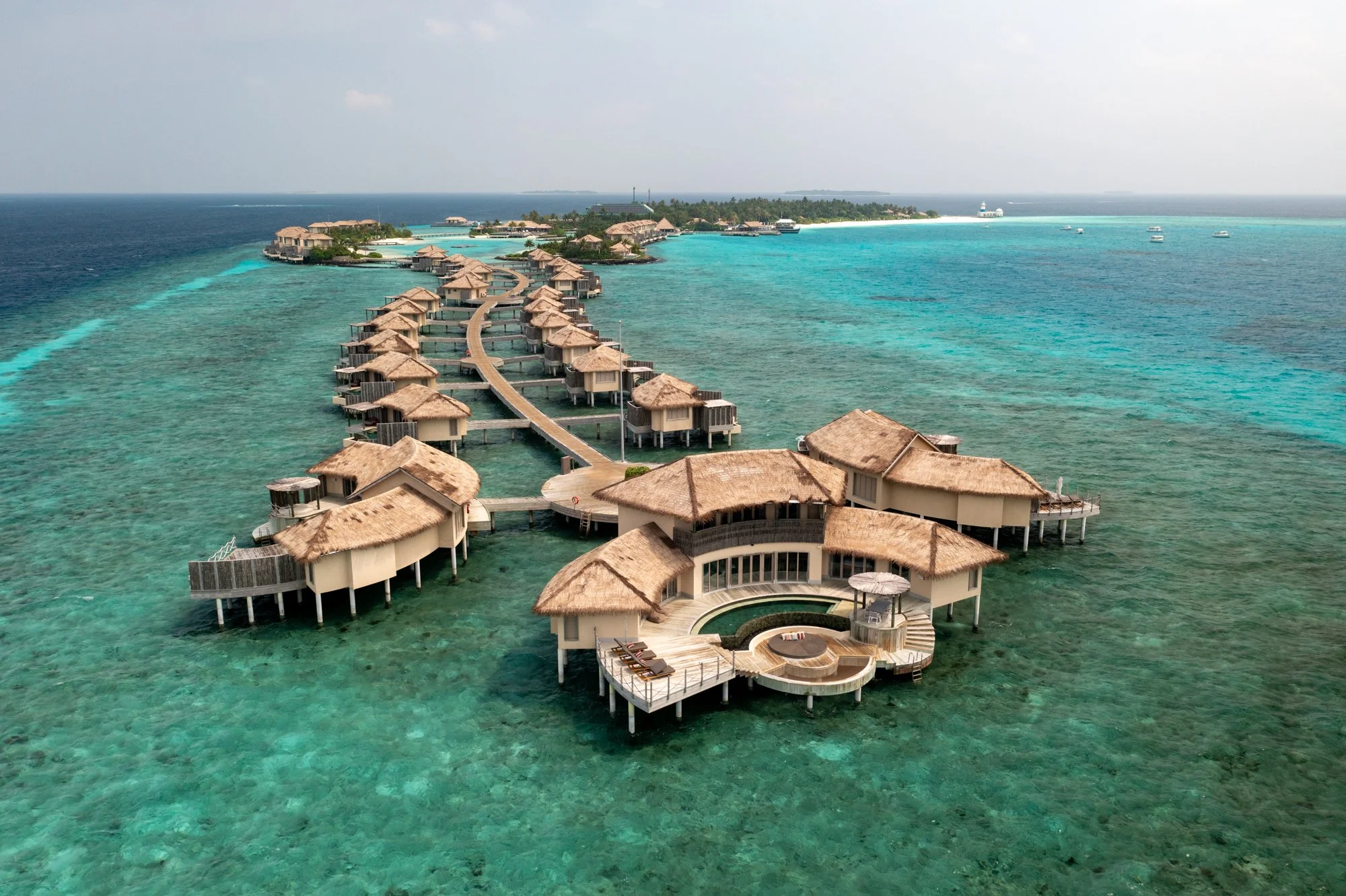 Aerial view of luxury overwater villas extending into the clear blue water of the Maldives.