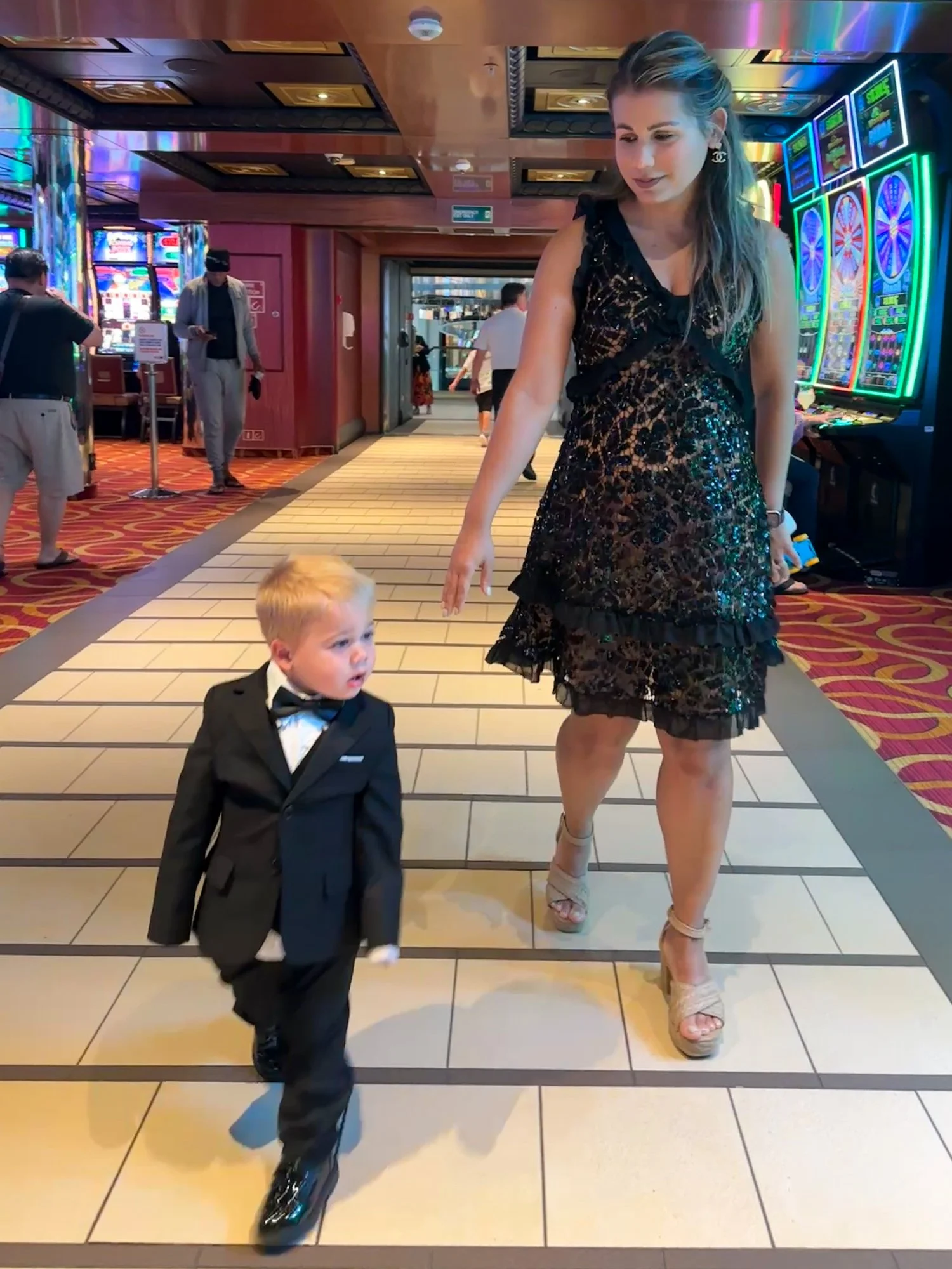 Amanda walking hand in hand with Daniel in a tuxedo aboard Carnival Radiance.