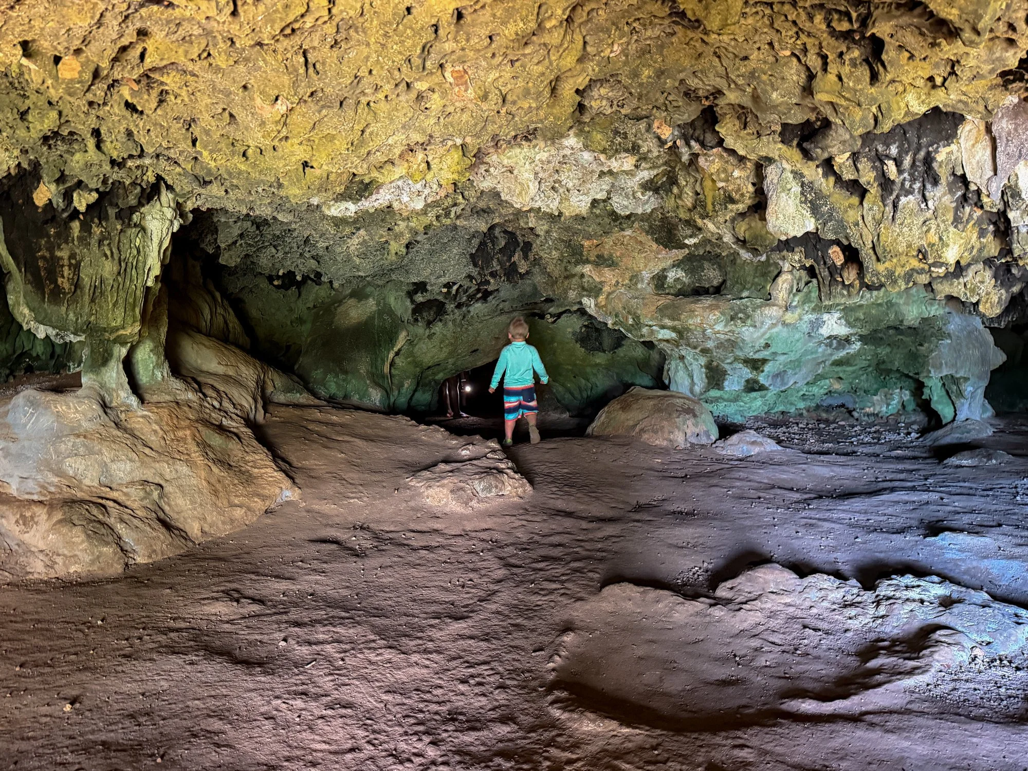 A young child explores the sculpted rock walls and passageways inside a coastal cave in Fiji.