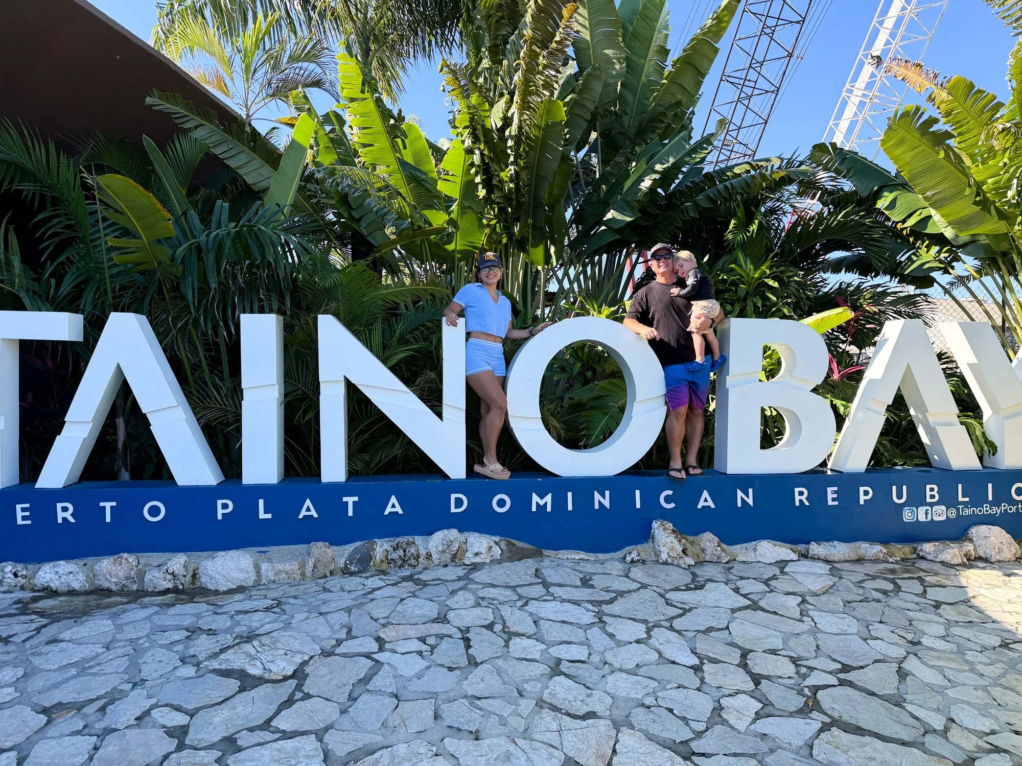 Family posing beside the Taino Bay Puerto Plata Dominican Republic sign.