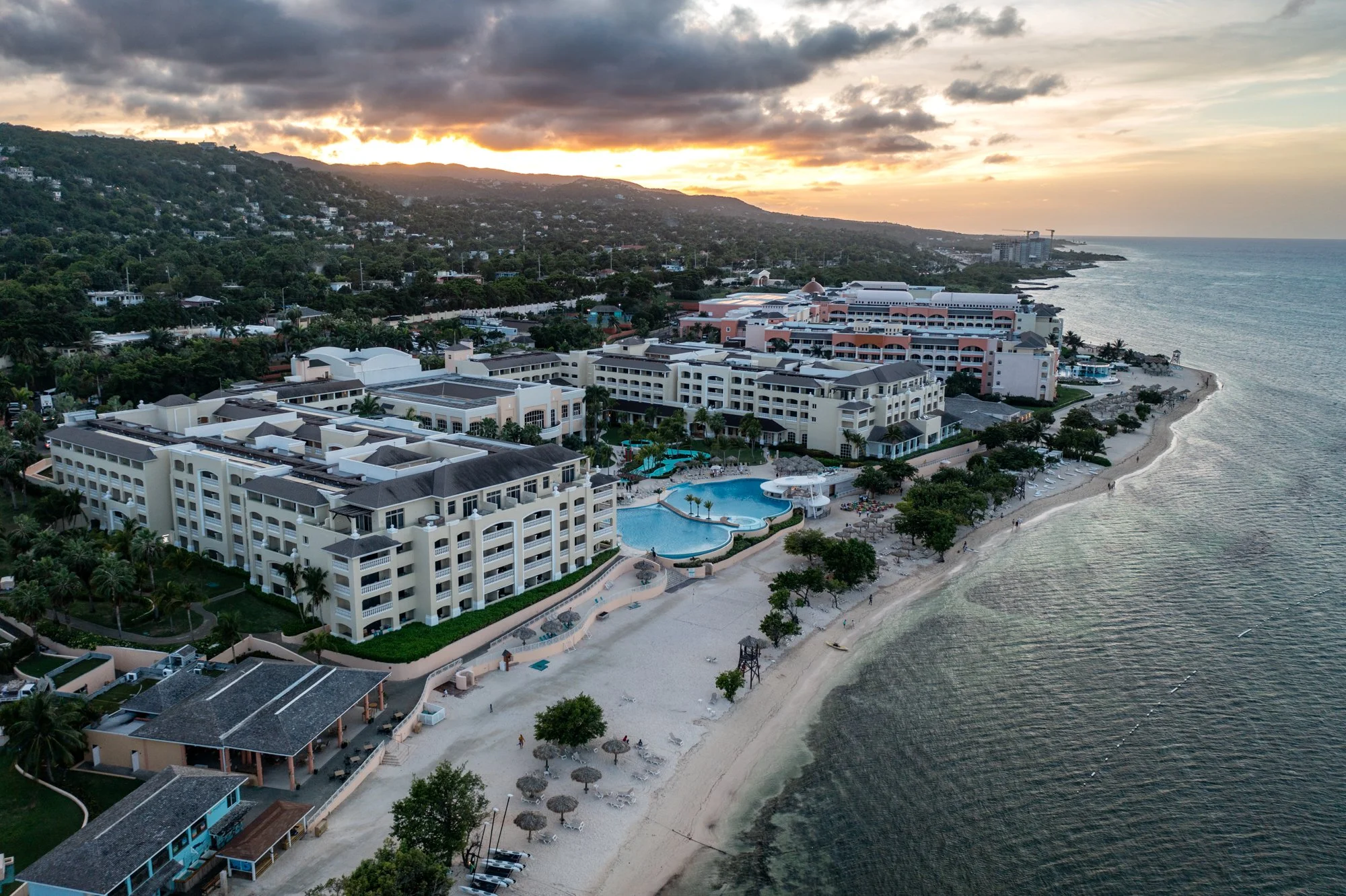 Aerial view of a beachfront resort and green hills at sunset on Jamaica’s north coast.