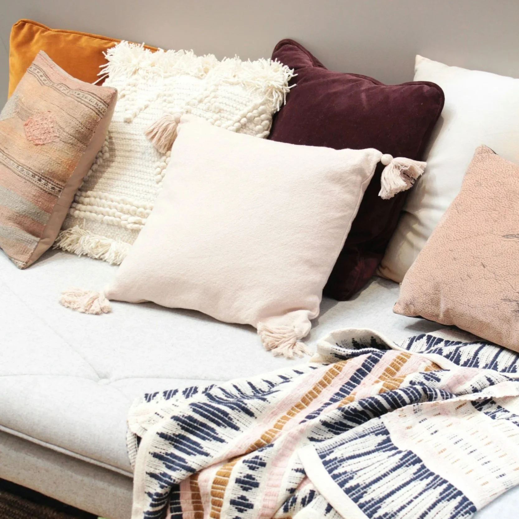 A cozy sofa decorated with various decorative pillows and a patterned throw blanket.
