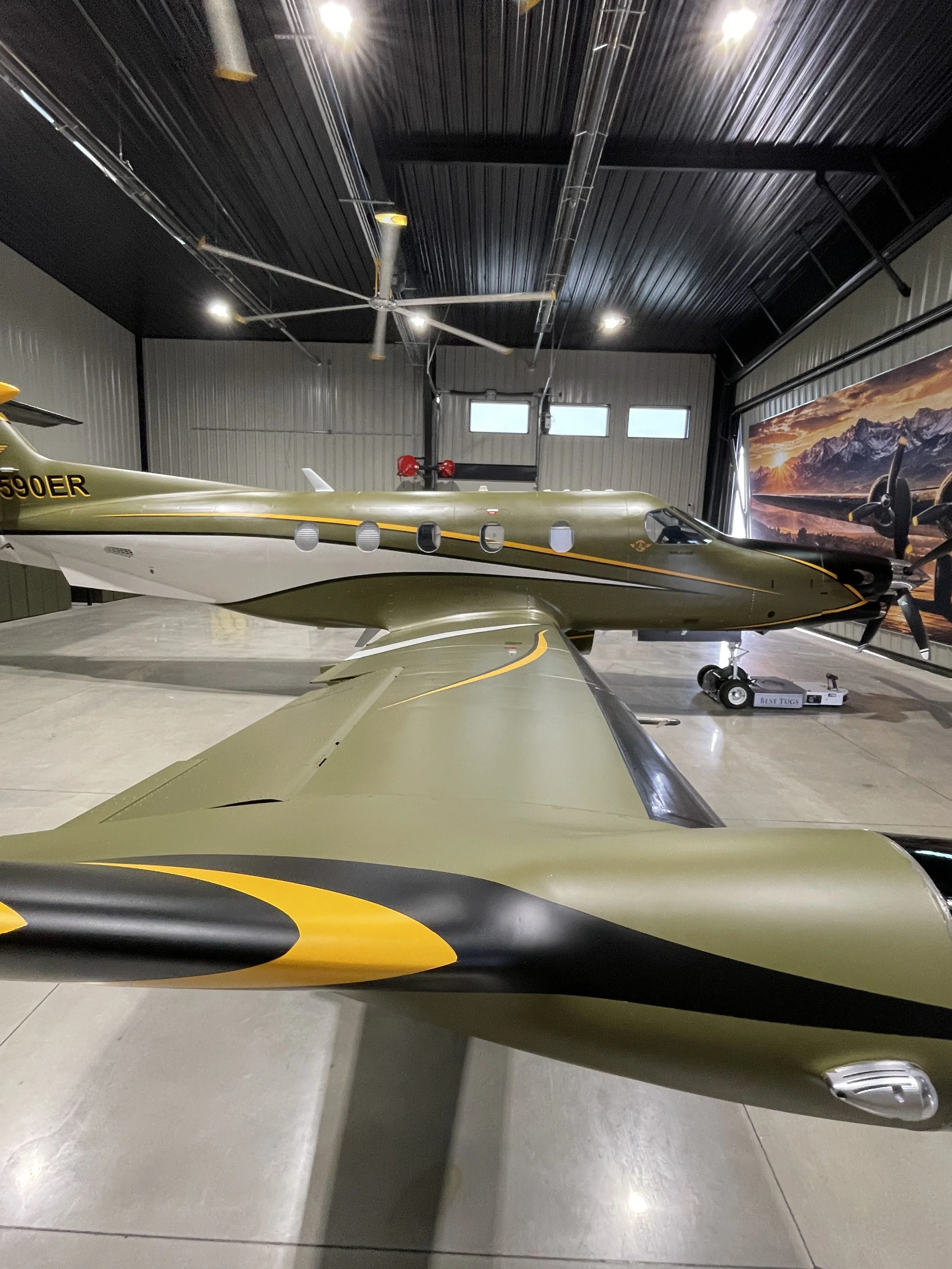 Ceramic coated matte Pilatus PC-12 in big hangar with plane image on the hangar door.