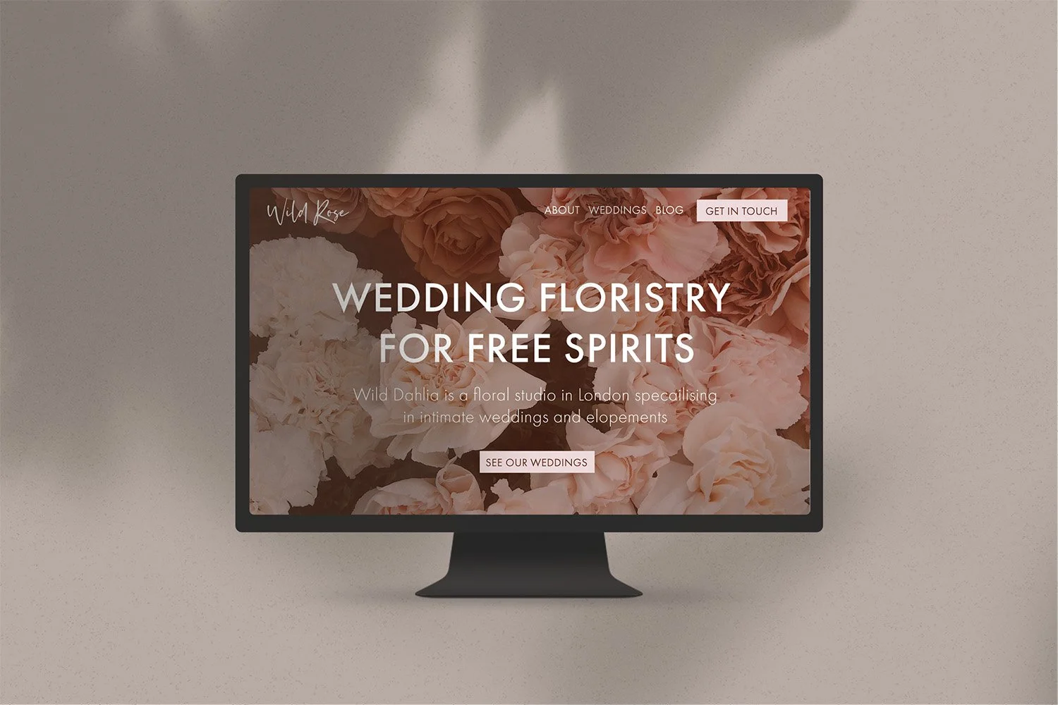 Wedding floristry website displayed on a computer monitor with a floral background, featuring menu options for About, Weddings, Blog, and a Get in Touch button.