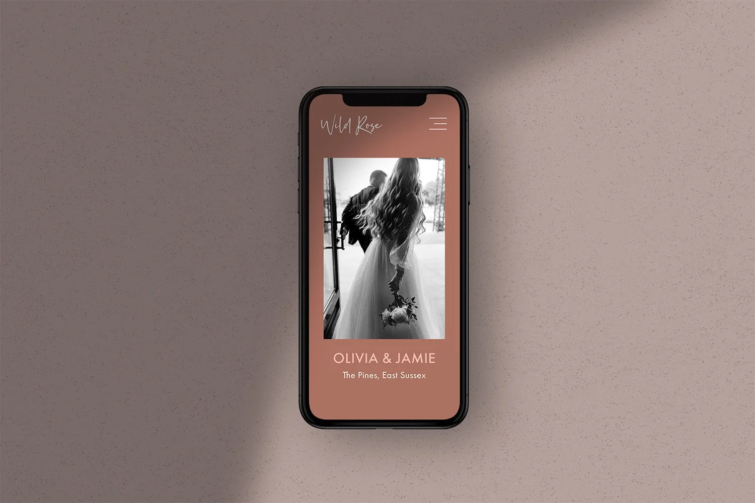 A smartphone screen displays a black and white wedding photo of a bride holding a bouquet, with text indicating Olivia & Jamie's wedding at The Pines, East Sussex.