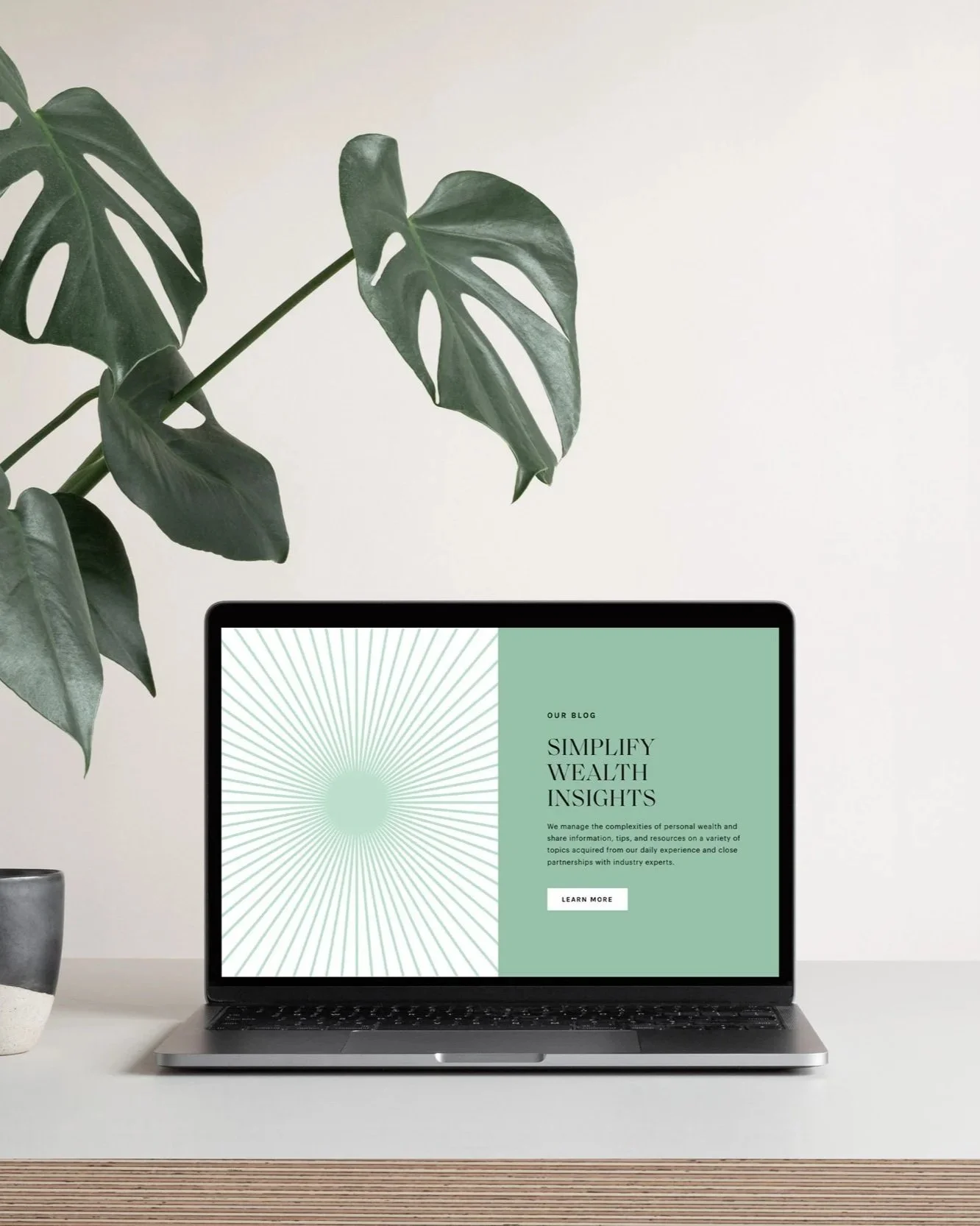Laptop displaying a blog page titled 'Simplify Wealth Insights' on a white desk with a leafy plant in a pot to the left.