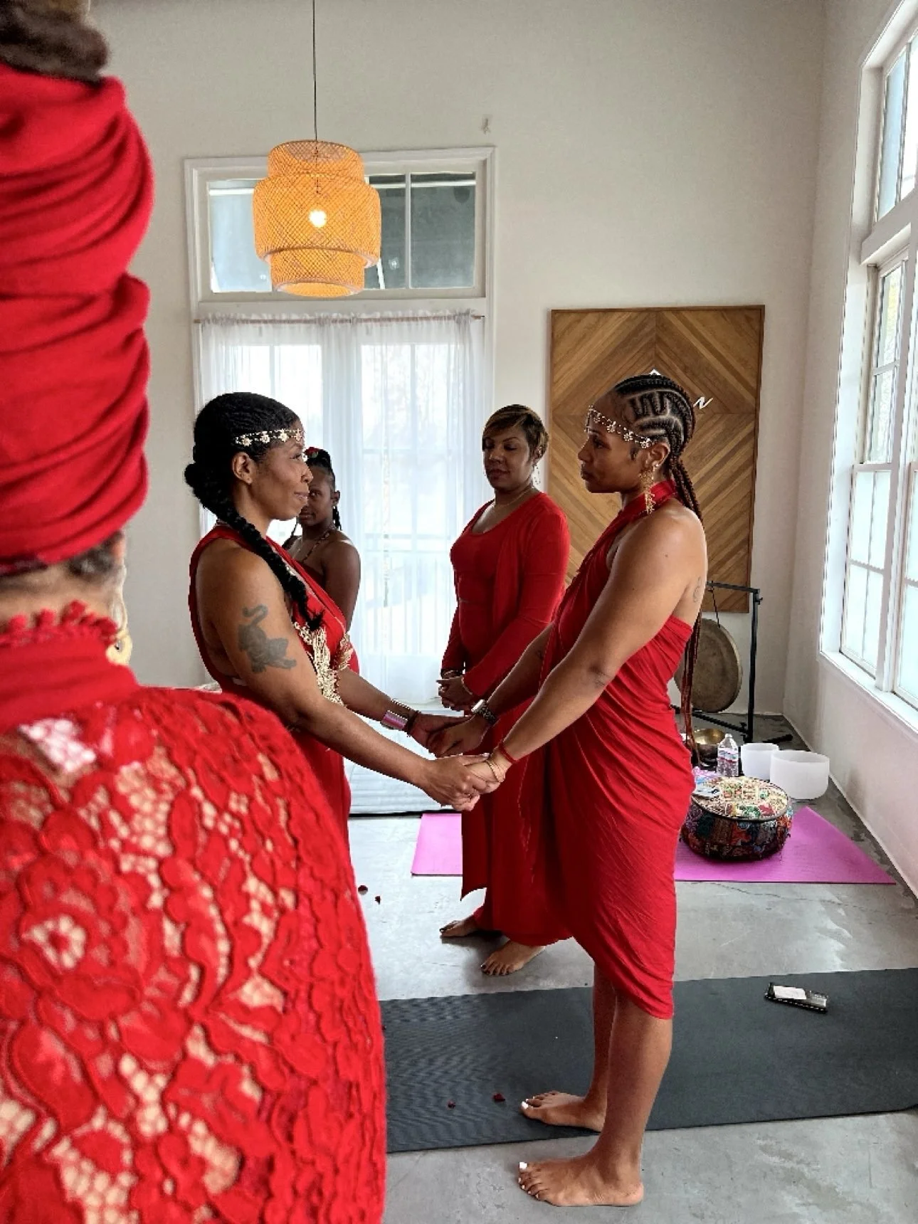 Ashley and another woman in red, hands joined in a circle — her photograph.