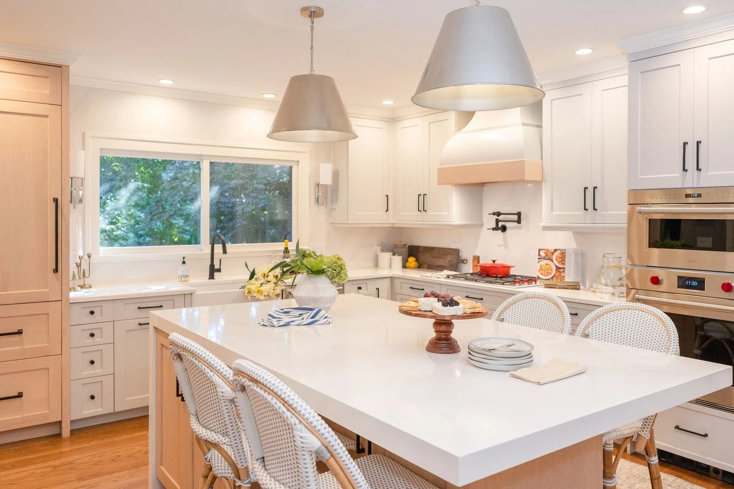 A kitchen that says gather here and stay awhile.

At this home, natural light pours in through oversized windows, highlighting custom cabinetry, sculptural pendant lighting, and a generous island perfect for wine nights or quiet mornings. Every detai