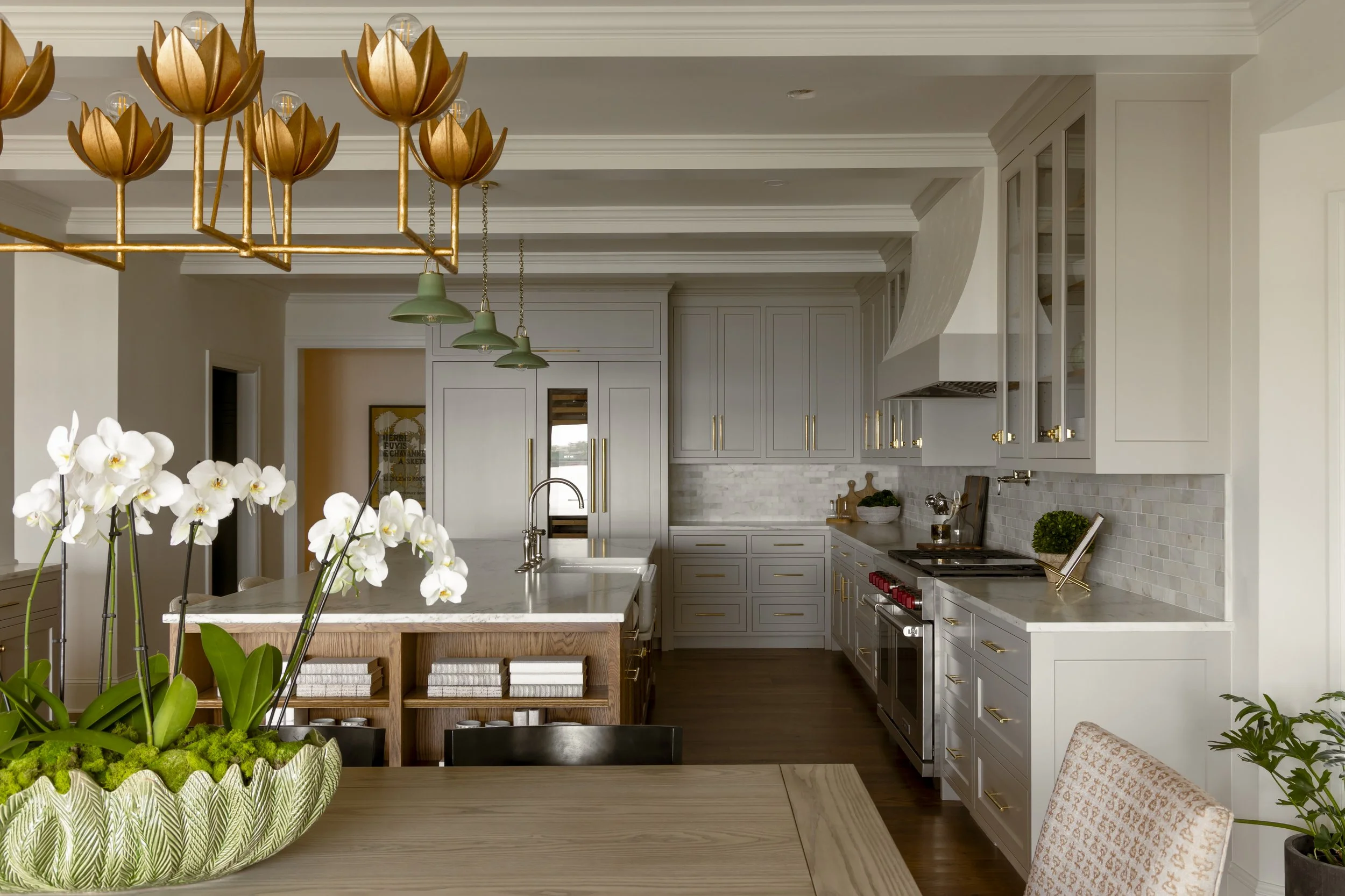 Modern kitchen with gray cabinets, white marble countertops, stainless steel appliances, and decorative plants and flowers
