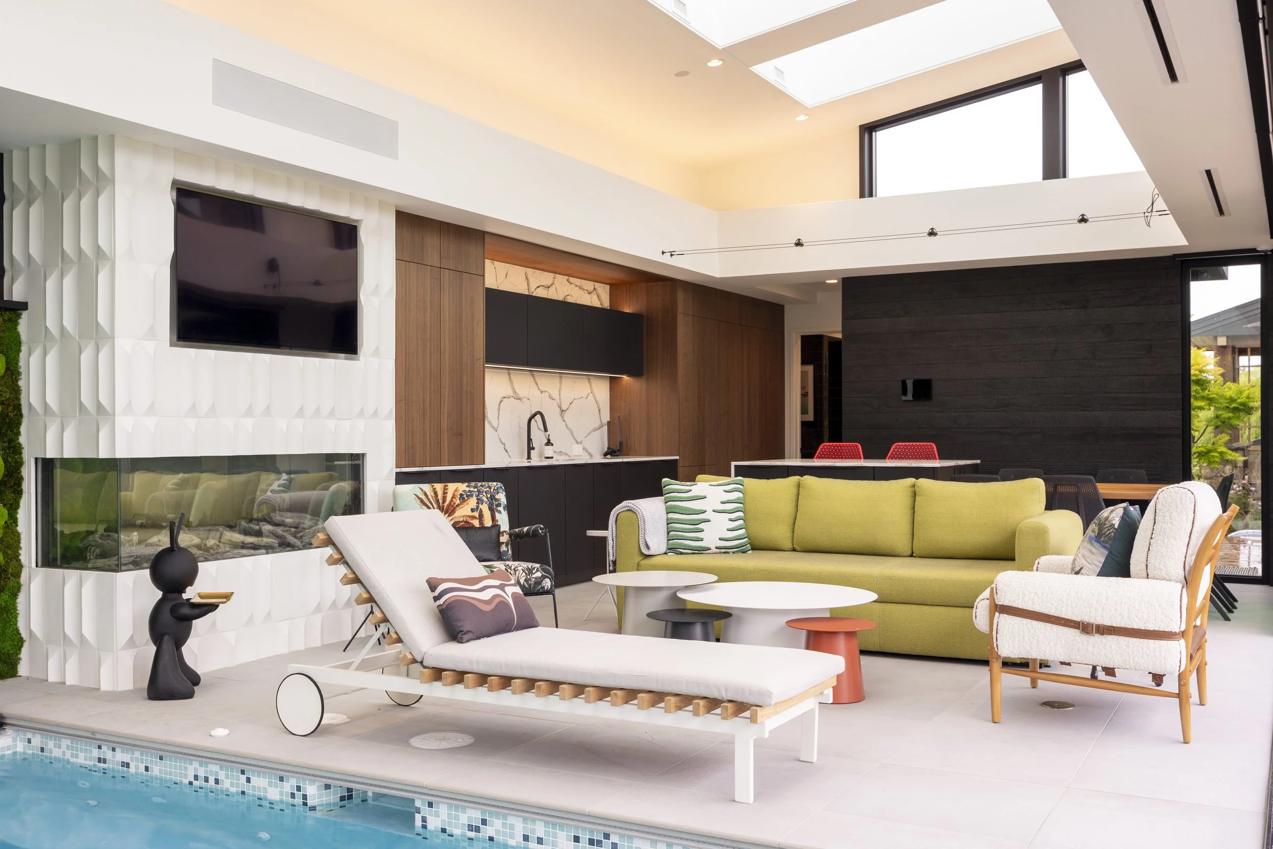 Modern indoor lounge area with a pool, colorful couches, and contemporary decor.