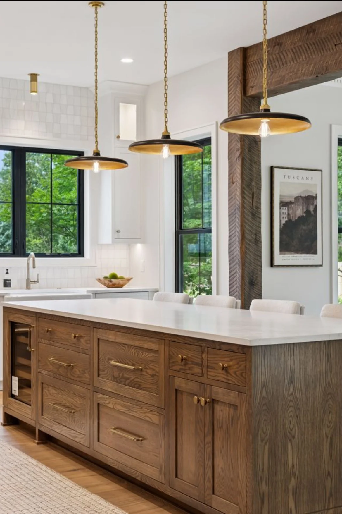 Modern kitchen with wooden cabinetry, white countertop, black-framed windows, and hanging pendant lights.
