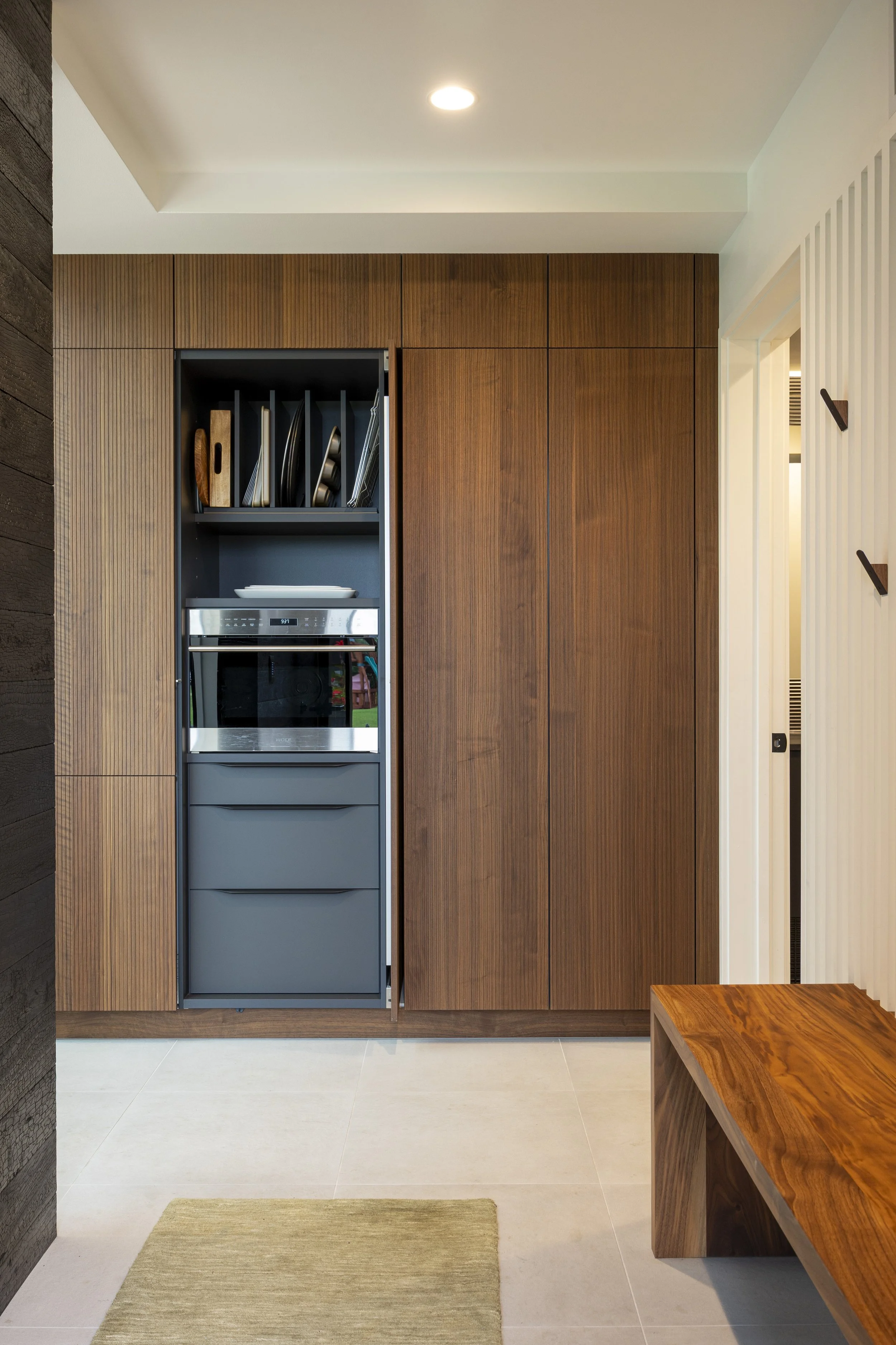 Modern kitchen with wooden cabinets, built-in oven, and a bench in the foreground.