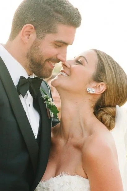 A bride and groom smile and look at each other on their wedding day, close-up of their faces.