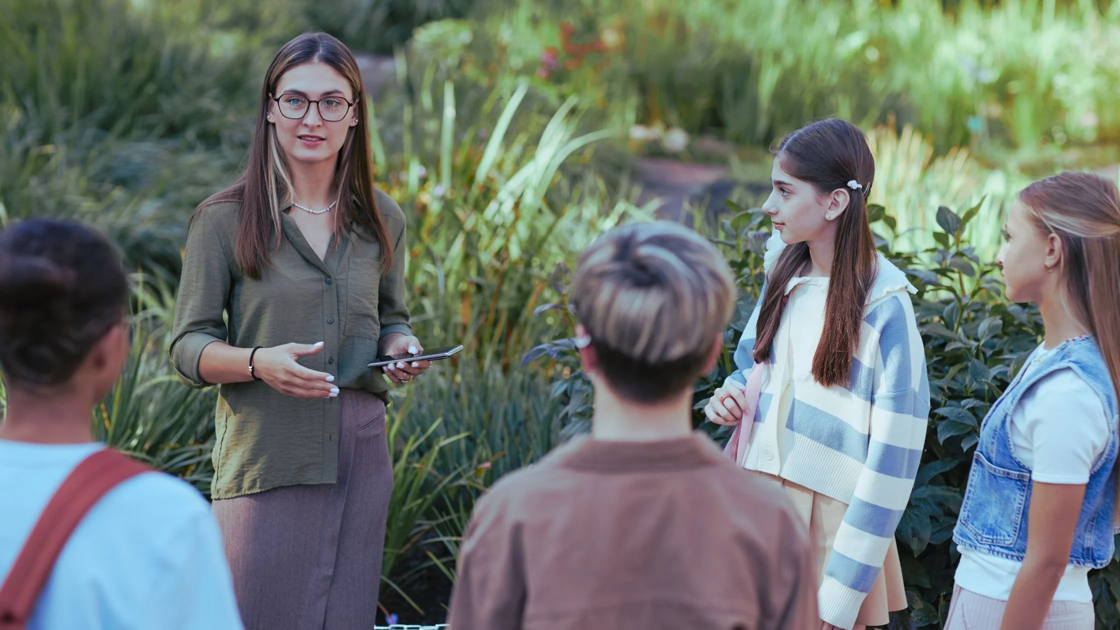 Teacher speaking with students outdoors during a school activity, representing community-focused education and school enrolments.